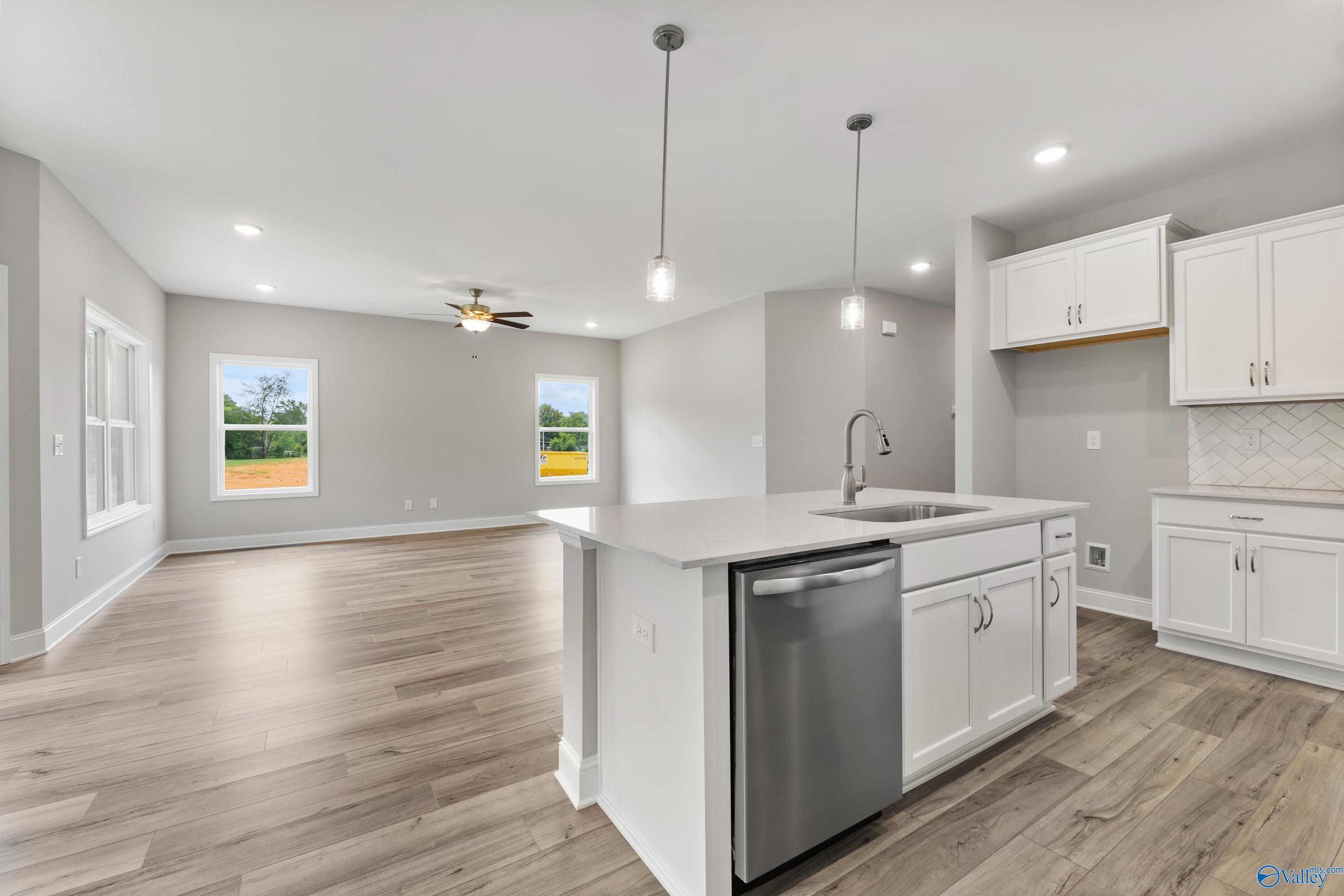 Open-concept kitchen with white cabinets, center island sink, stainless dishwasher, and large windows in The Franklin home by Davidson Homes, Huntsville AL