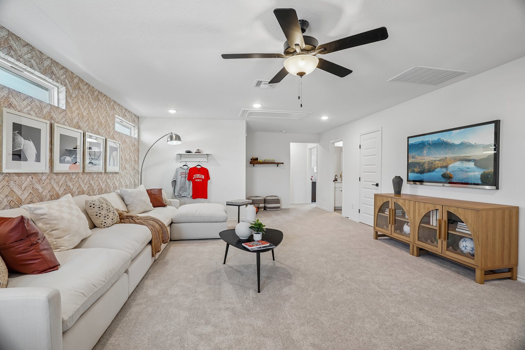 Spacious living room at Fairway Crossing in Converse, TX by Davidson Homes with white sectional and herringbone accent wall.