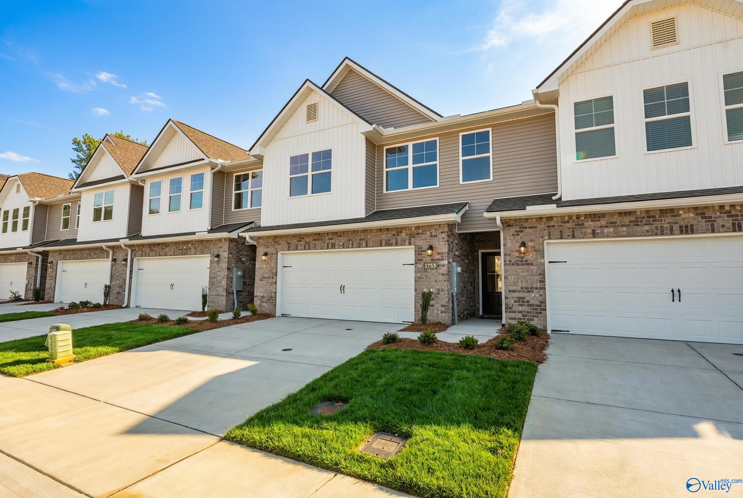 Row of modern 2-story townhomes with 2-car garages, brick accents, and lush lawns in Pavilion, Huntsville, Alabama by Davidson Homes