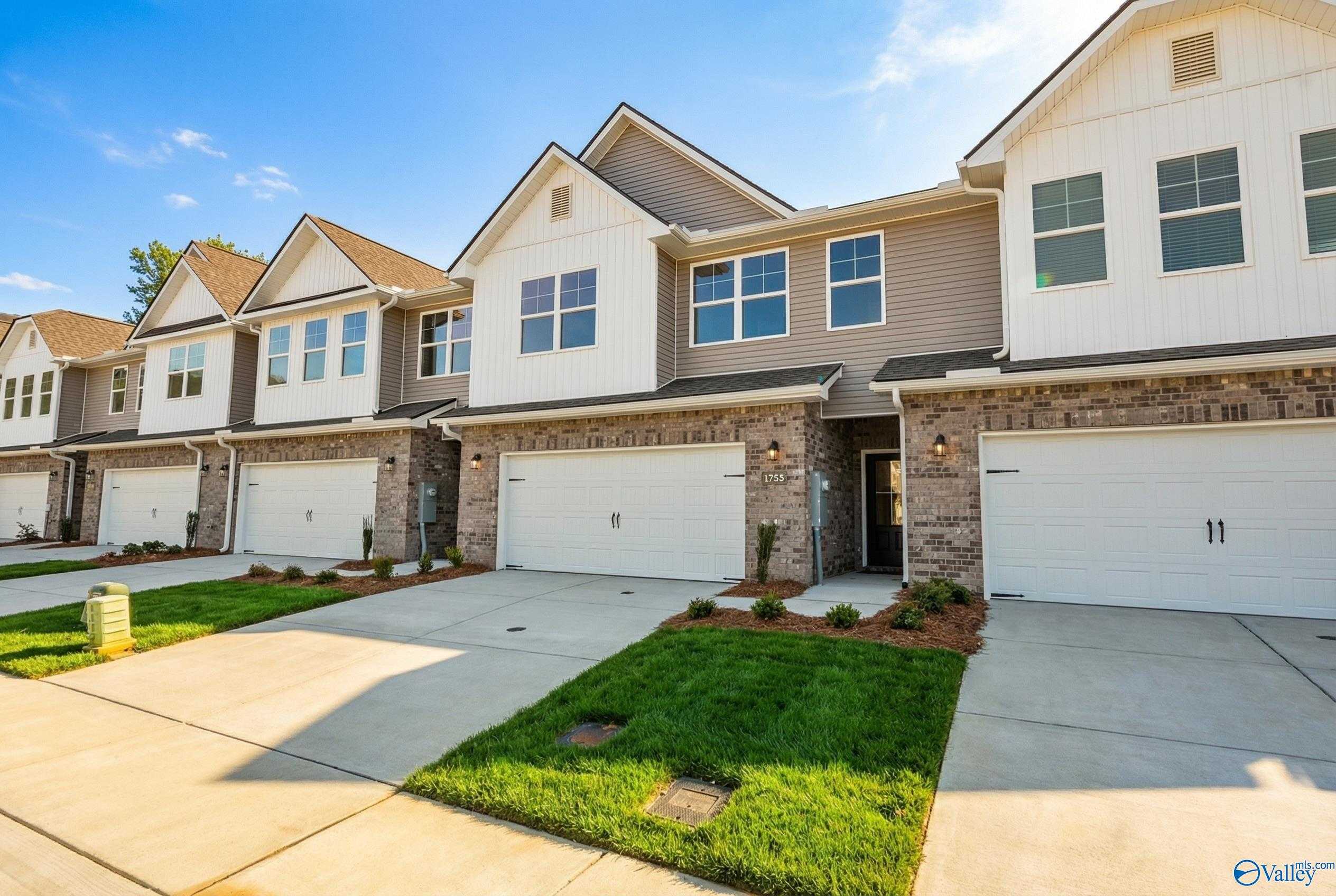 Row of modern 2-story townhomes with 2-car garages, brick accents, and lush lawns in Pavilion, Huntsville, Alabama by Davidson Homes