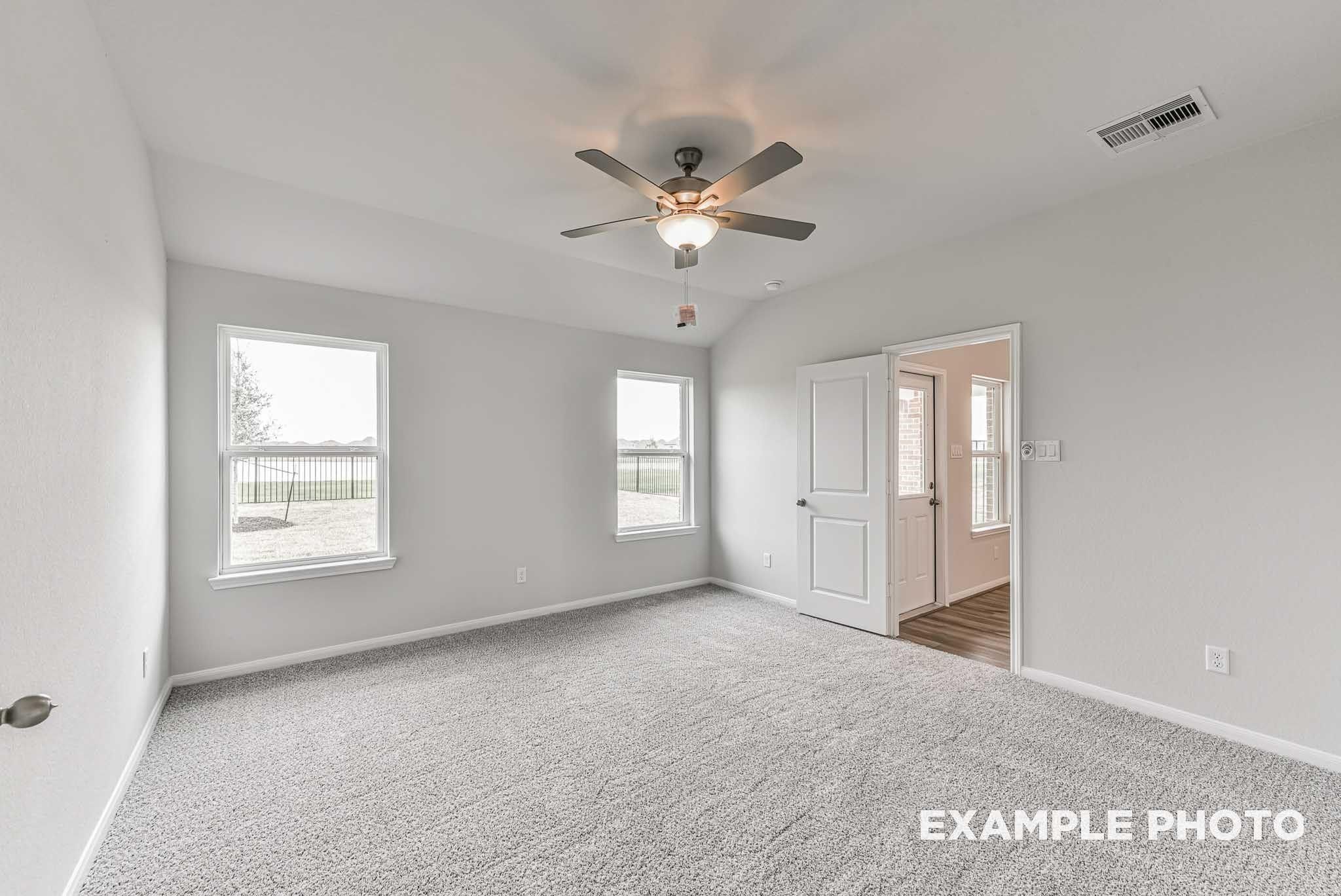 Bright carpeted bedroom with ceiling fan, dual windows, and backyard views in Davidson Homes The Costa A, River Ranch Meadows, Dayton, Texas