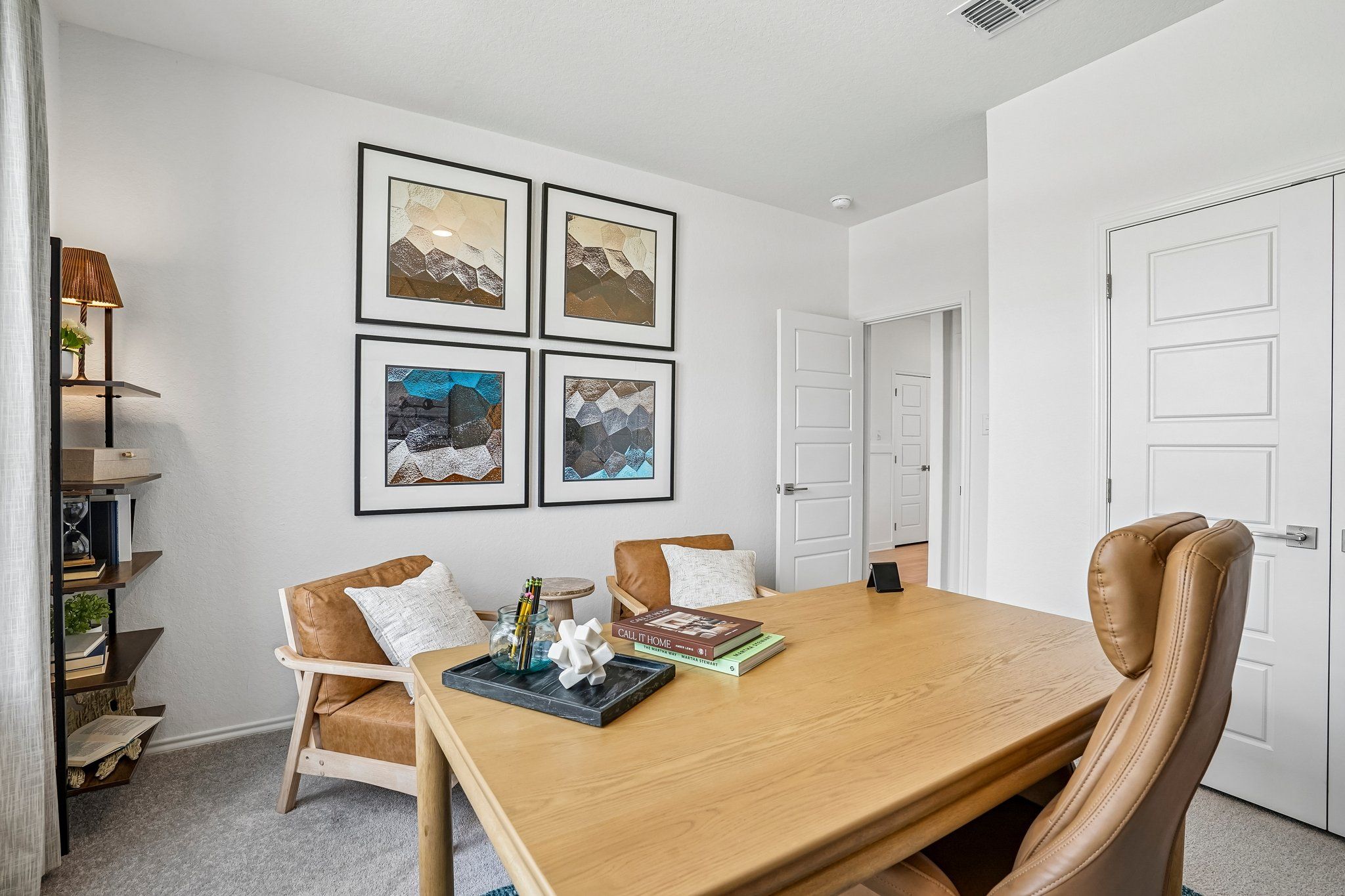 Modern home office at Morgan Meadows in San Antonio with wood desk, leather chairs, and contemporary wall art by Davidson Homes.