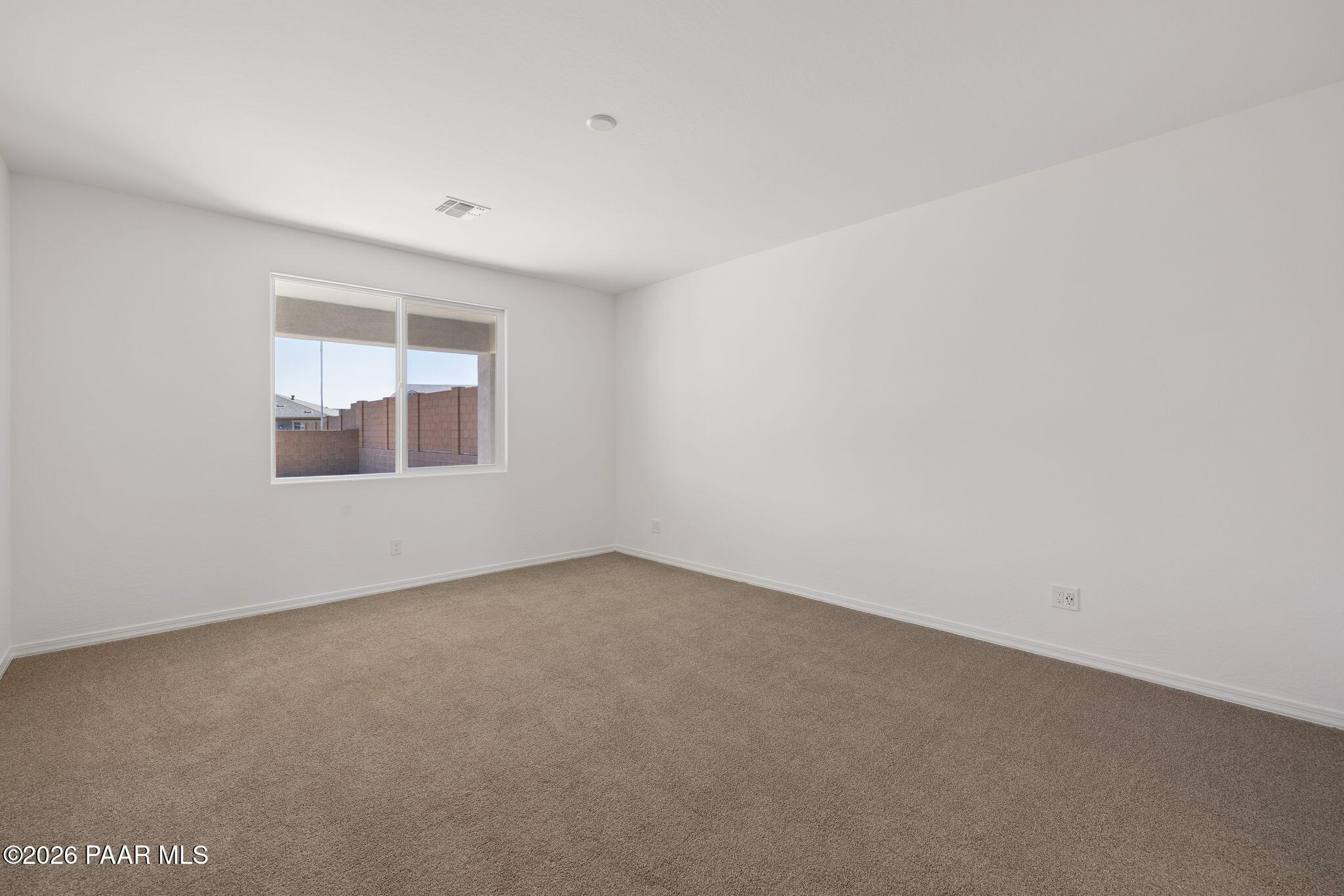 Empty bedroom with beige carpet, white walls, large window, and desert view in Davidson Homes The Monarch A, Prescott AZ