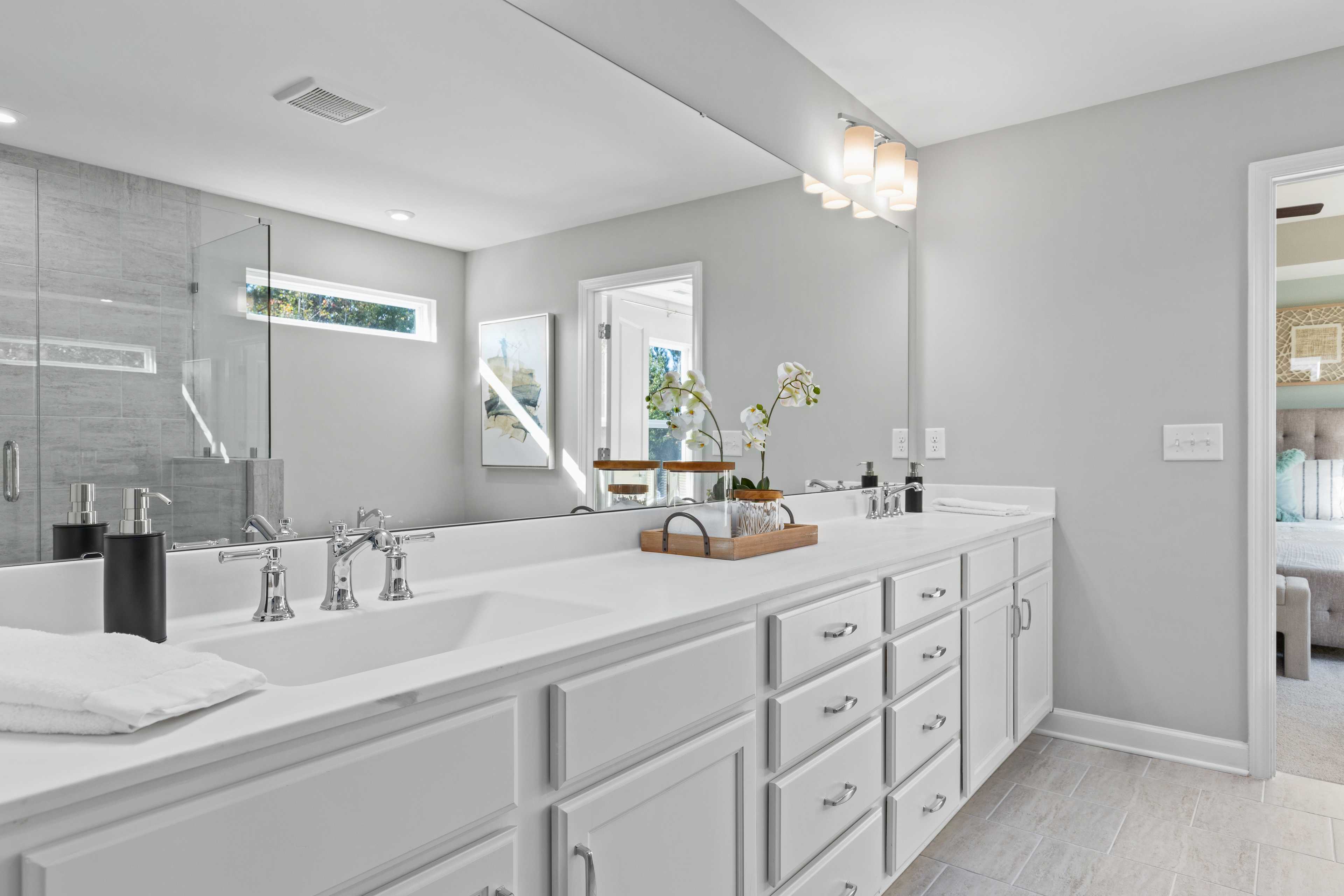 Luxury master bathroom at Enclave at Belmont in Belmont NC with double white vanity, large mirror and glass shower