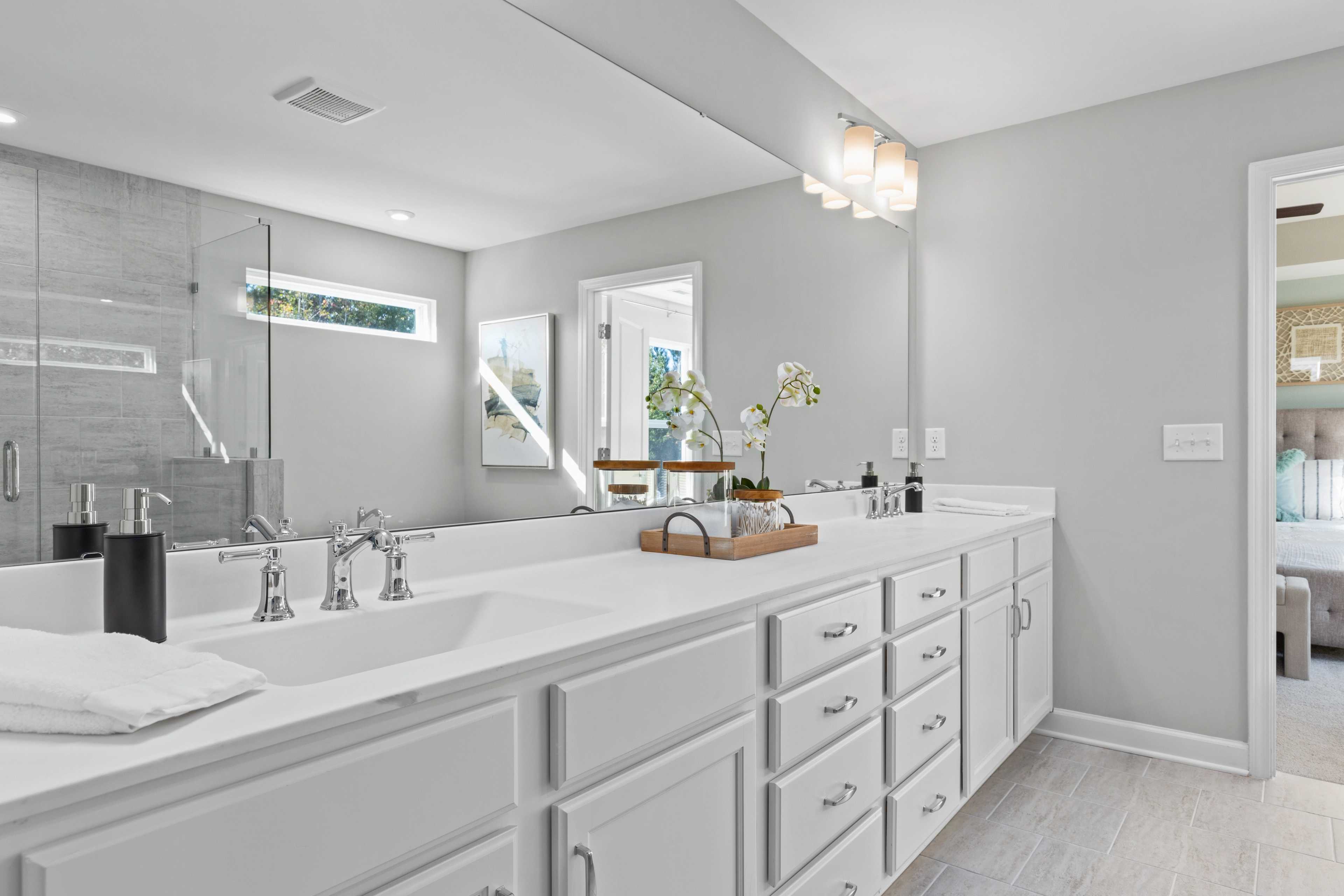 Luxury master bathroom at Enclave at Belmont in Belmont NC with double white vanity, large mirror and glass shower