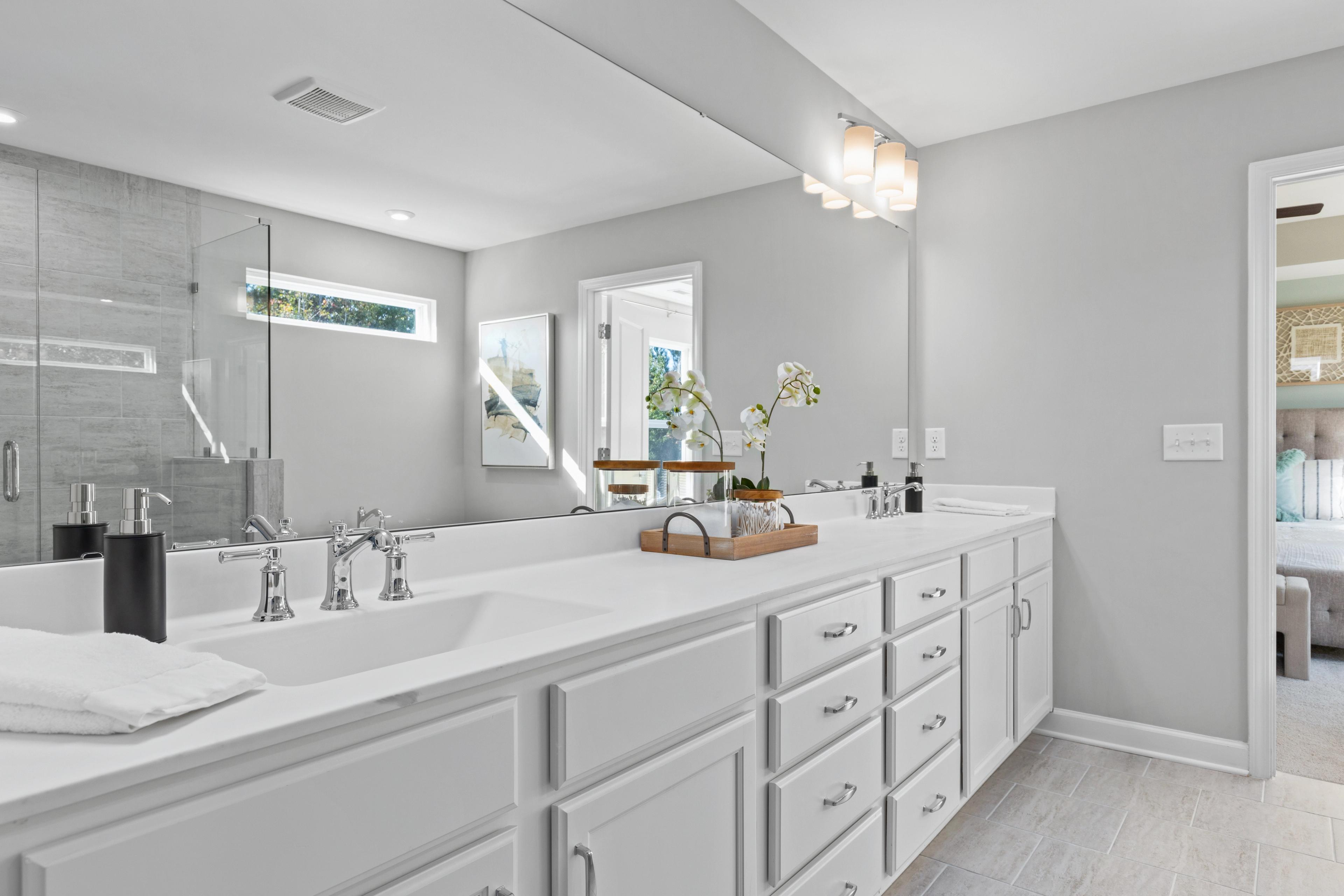 Luxury master bathroom at Enclave at Belmont in Belmont NC with double white vanity, large mirror and glass shower
