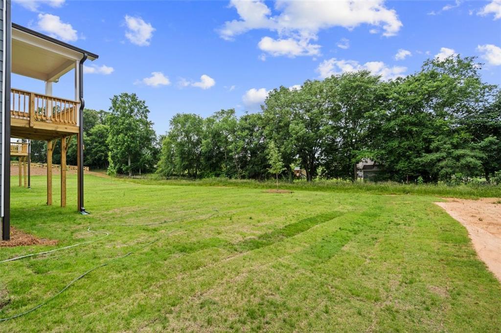 Two-story Davidson Homes elevation with upper deck and covered porch overlooking lush green yard and trees at Wehunt Meadows, Hoschton