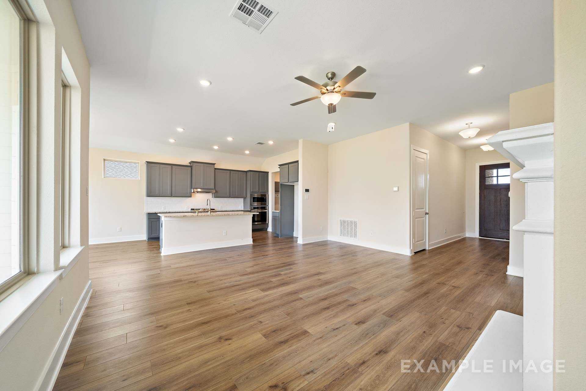 Spacious open-concept kitchen and living area in The Diana C with gray cabinets, large island, ceiling fan, and hardwood floors
