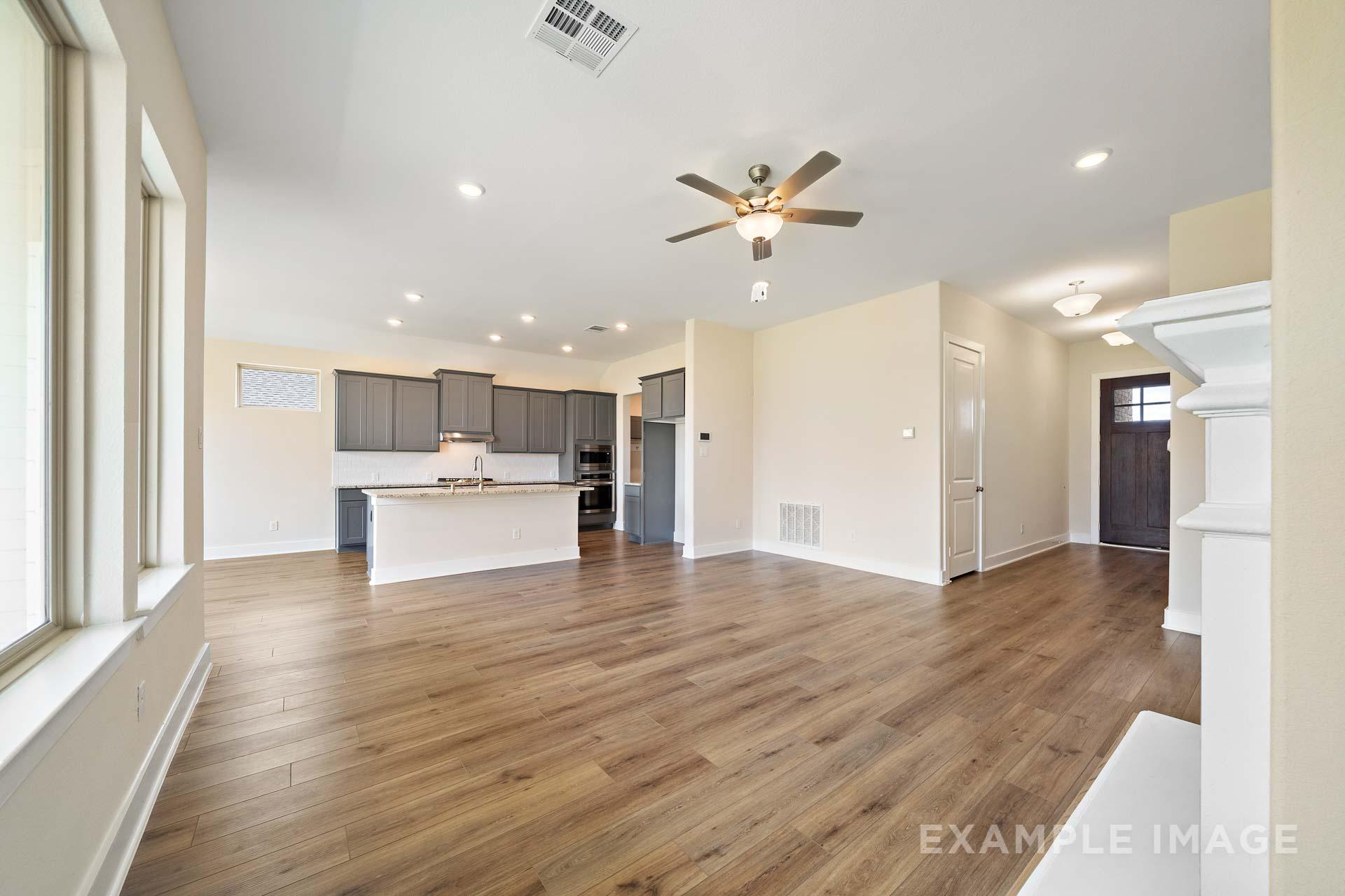 Spacious open-concept kitchen and living area in The Diana C with gray cabinets, large island, ceiling fan, and hardwood floors