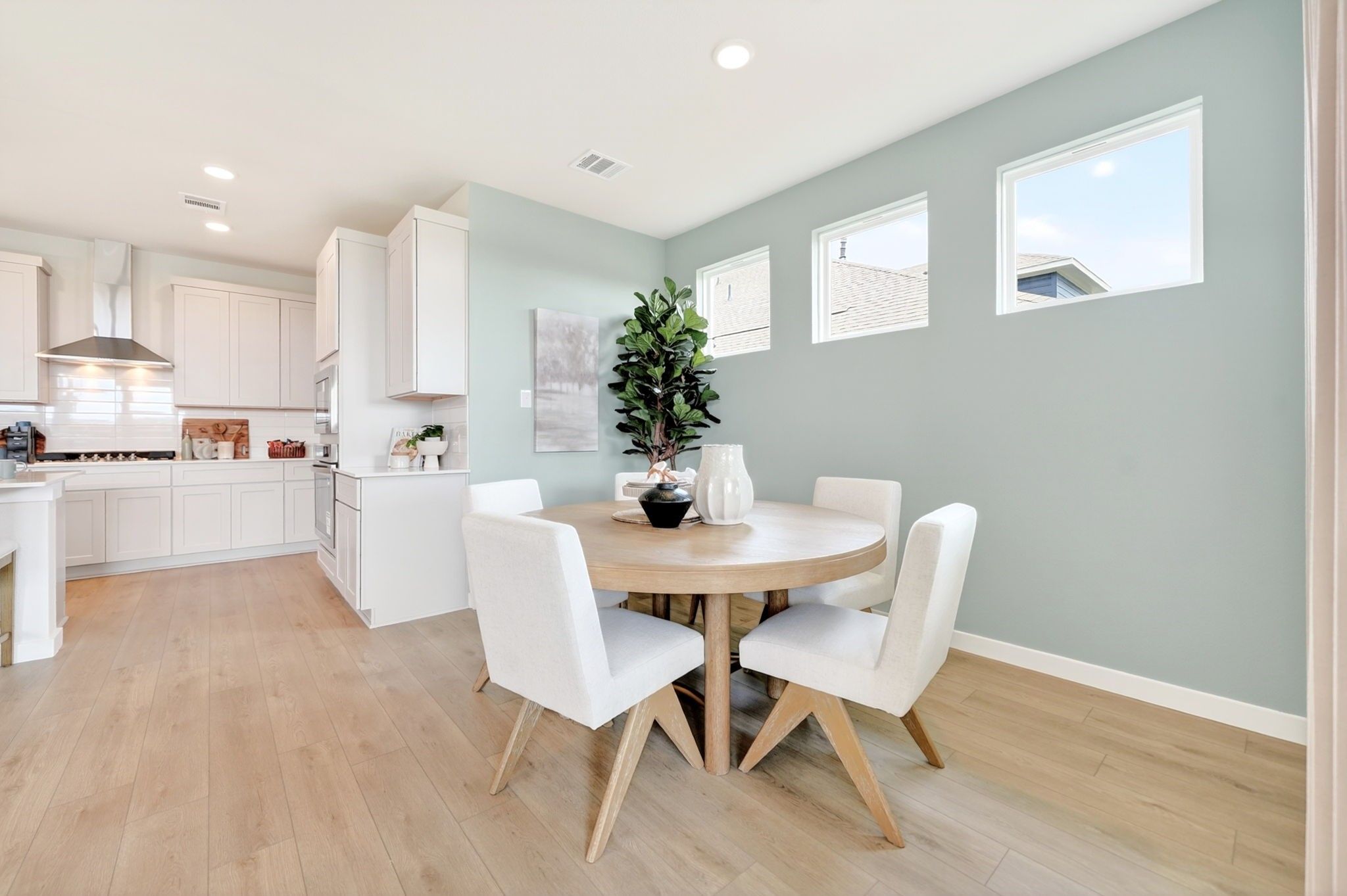 Bright breakfast nook with round wood table and white chairs in The Laurel M floor plan at Parks at Foster Crossing, Anna.