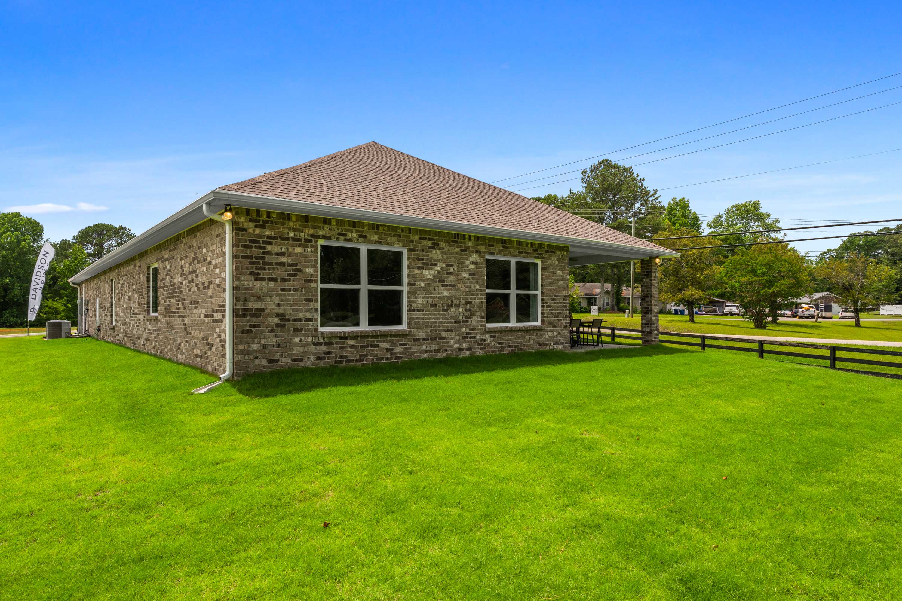 Brick home exterior at The Highlands in Arab AL with gabled roof, covered carport, lush green lawn and wooden fence