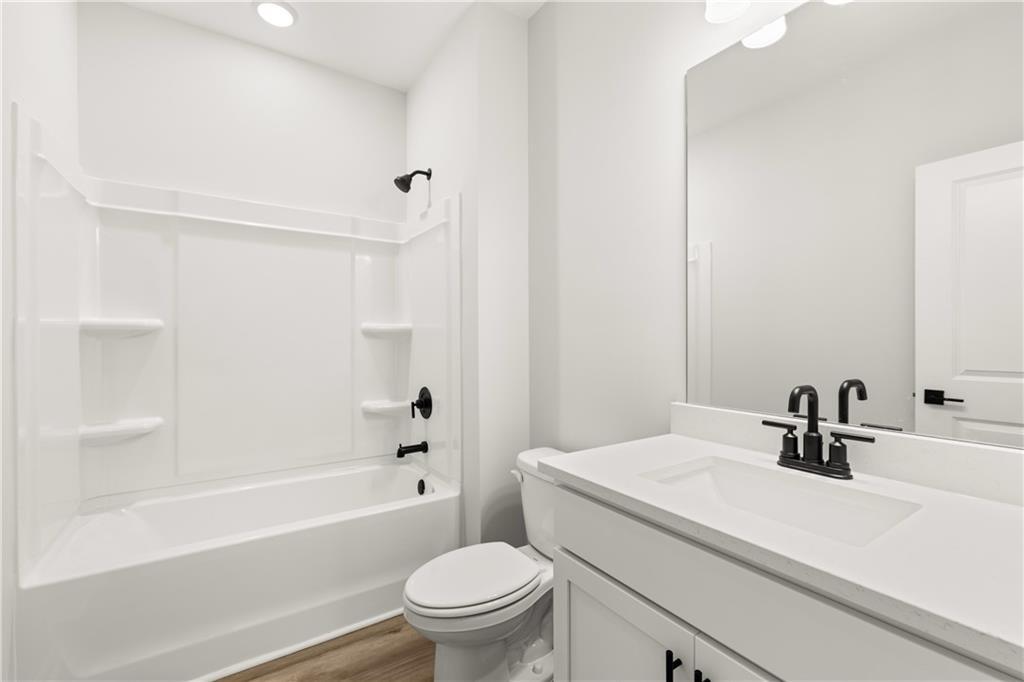 Modern white bathroom with walk-in shower, soaking tub, and single vanity in Davidson Homes The Hickory B, Winder, Georgia