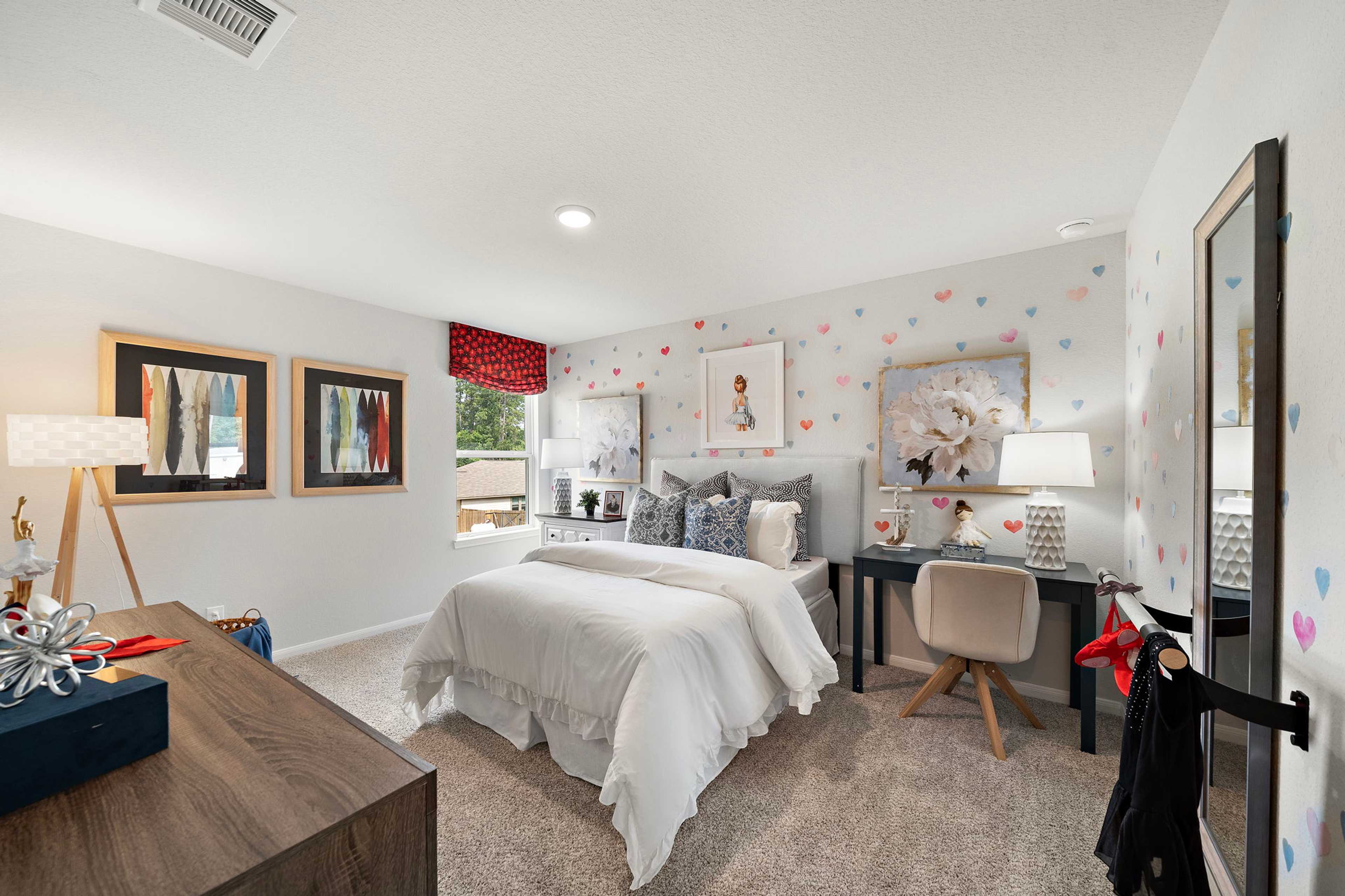 Charming girl's bedroom at Liberty Estates in Cleveland Texas featuring white bed, pink heart wall decals, desk and modern decor