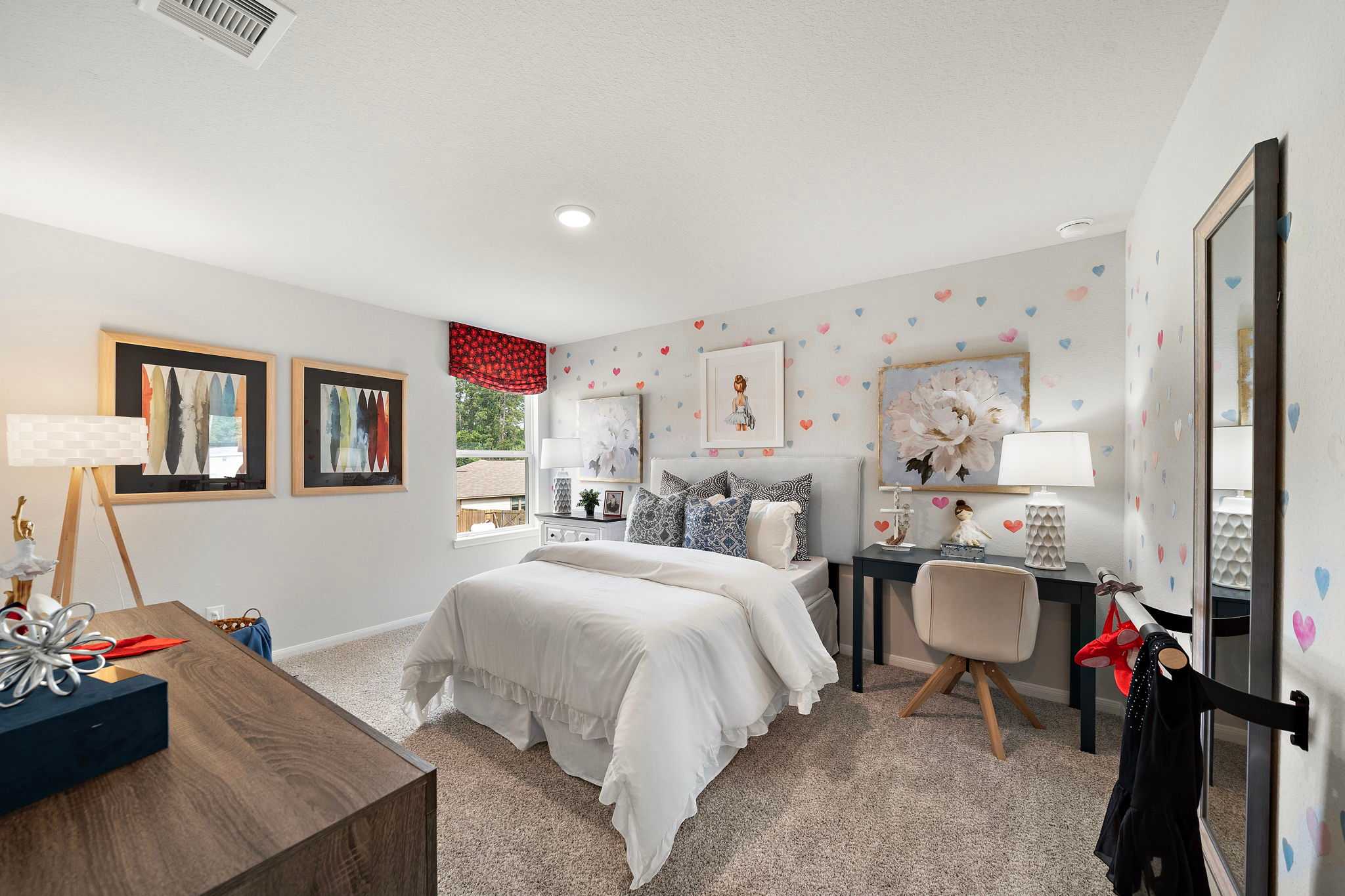 Charming girl's bedroom at Liberty Estates in Cleveland Texas featuring white bed, pink heart wall decals, desk and modern decor