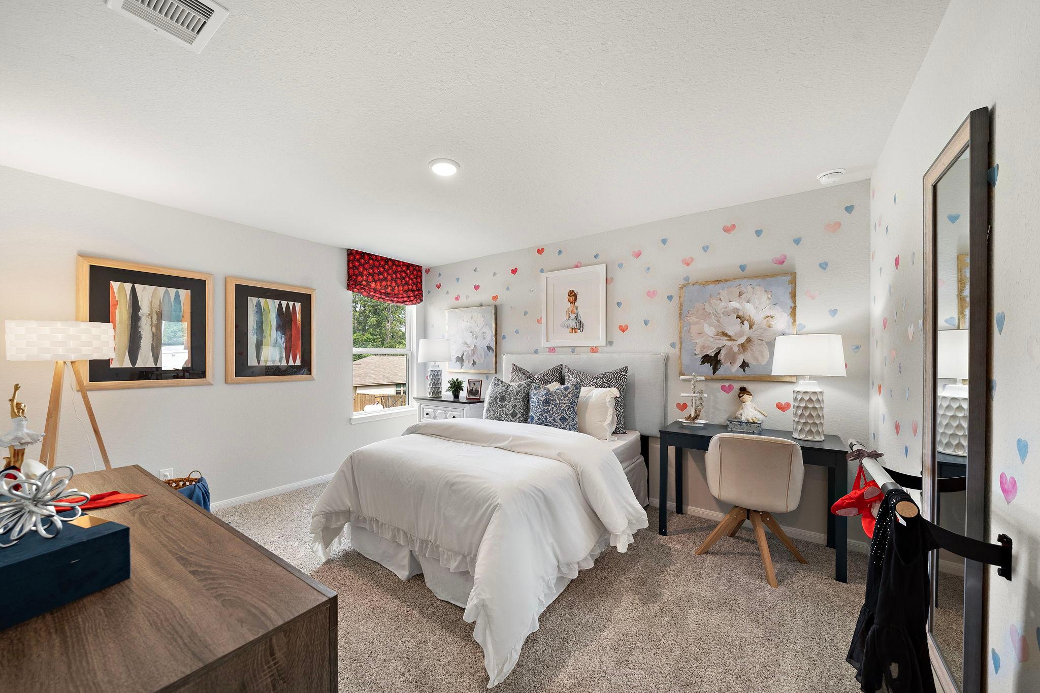 Charming girl's bedroom at Liberty Estates in Cleveland Texas featuring white bed, pink heart wall decals, desk and modern decor