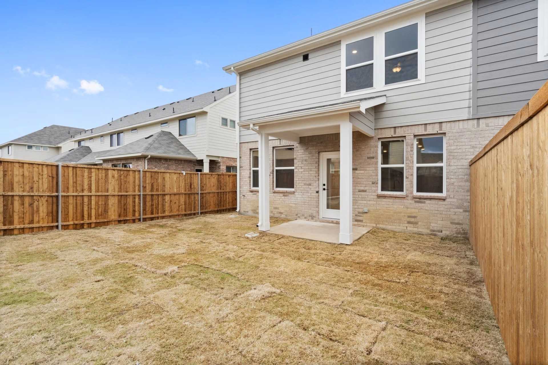 Spacious fenced backyard with covered patio and modern exterior in 3-bedroom Davidson Homes The Wake D, Lake Park Villas, Wylie, Texas
