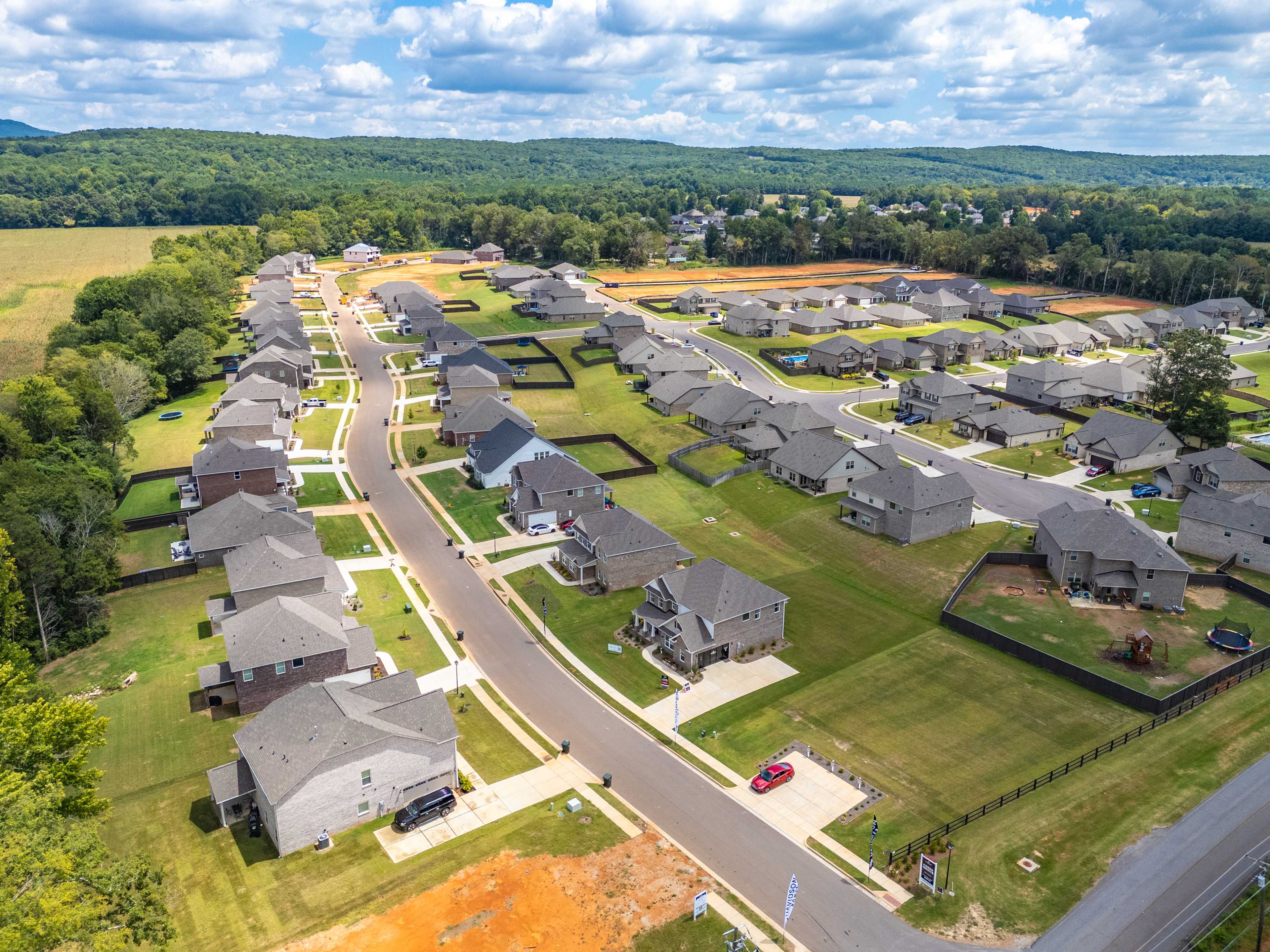 Aerial view of new homes in Creek Grove, New Market Alabama with streets, green lawns, woods, and construction areas