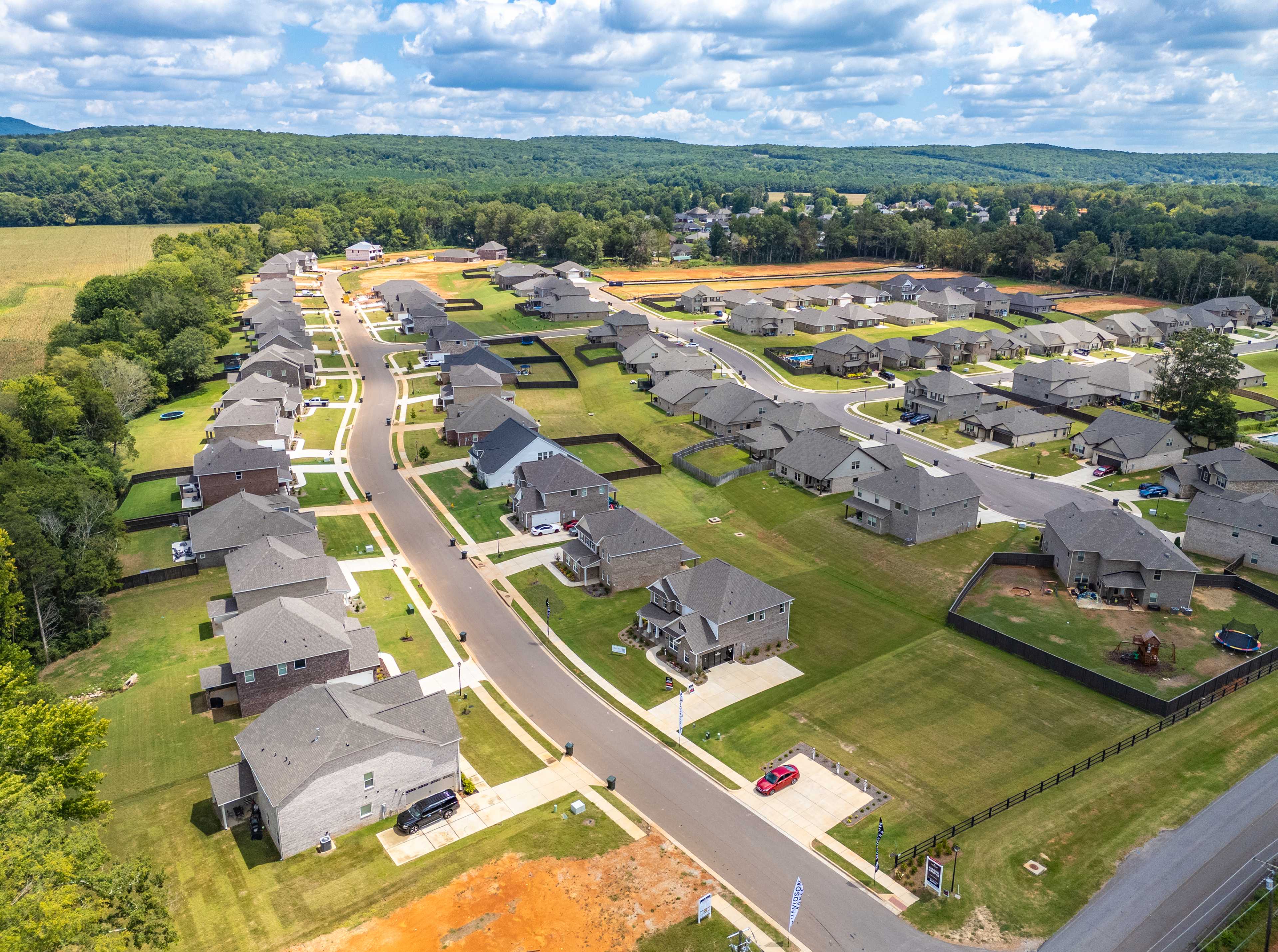 Aerial view of new homes in Creek Grove, New Market Alabama with streets, green lawns, woods, and construction areas