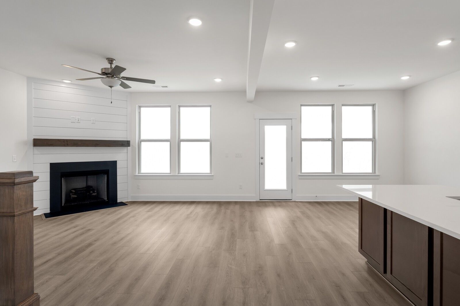 Open-concept living room with shiplap fireplace, hardwood floors, and kitchen island in Davidson Homes The Willow C, Gallatin, TN