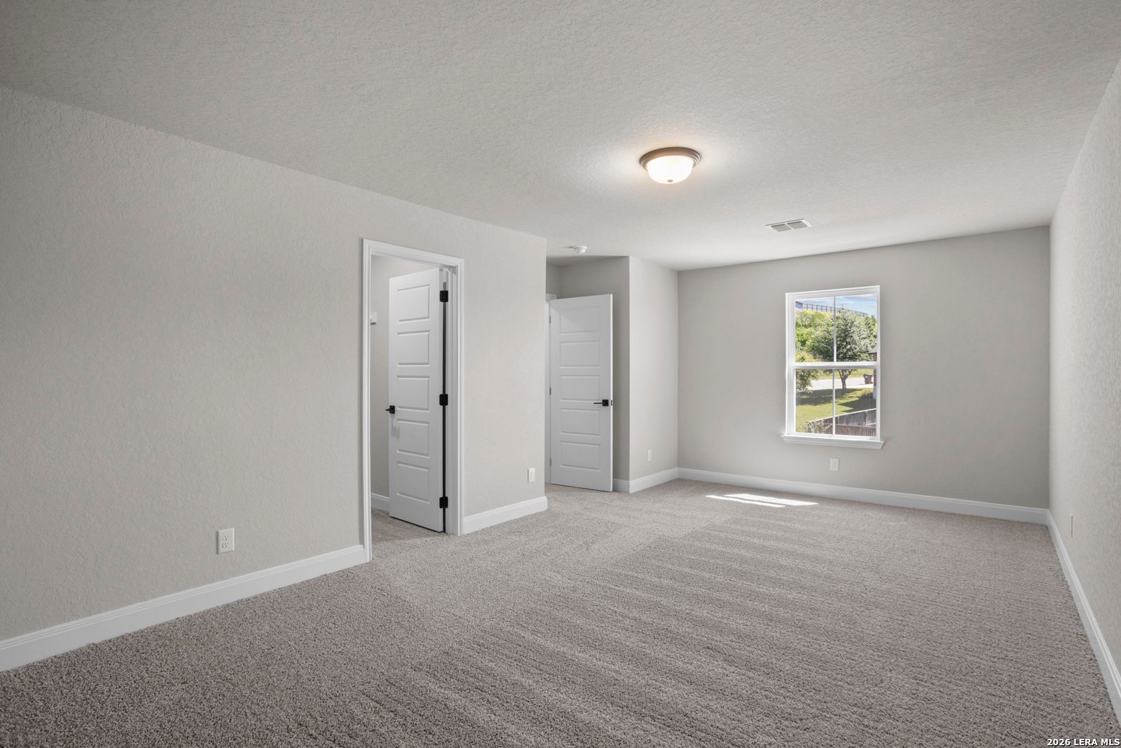 Spacious carpeted bedroom with neutral walls and natural light in The Jennings G floor plan at Ladera, San Antonio.
