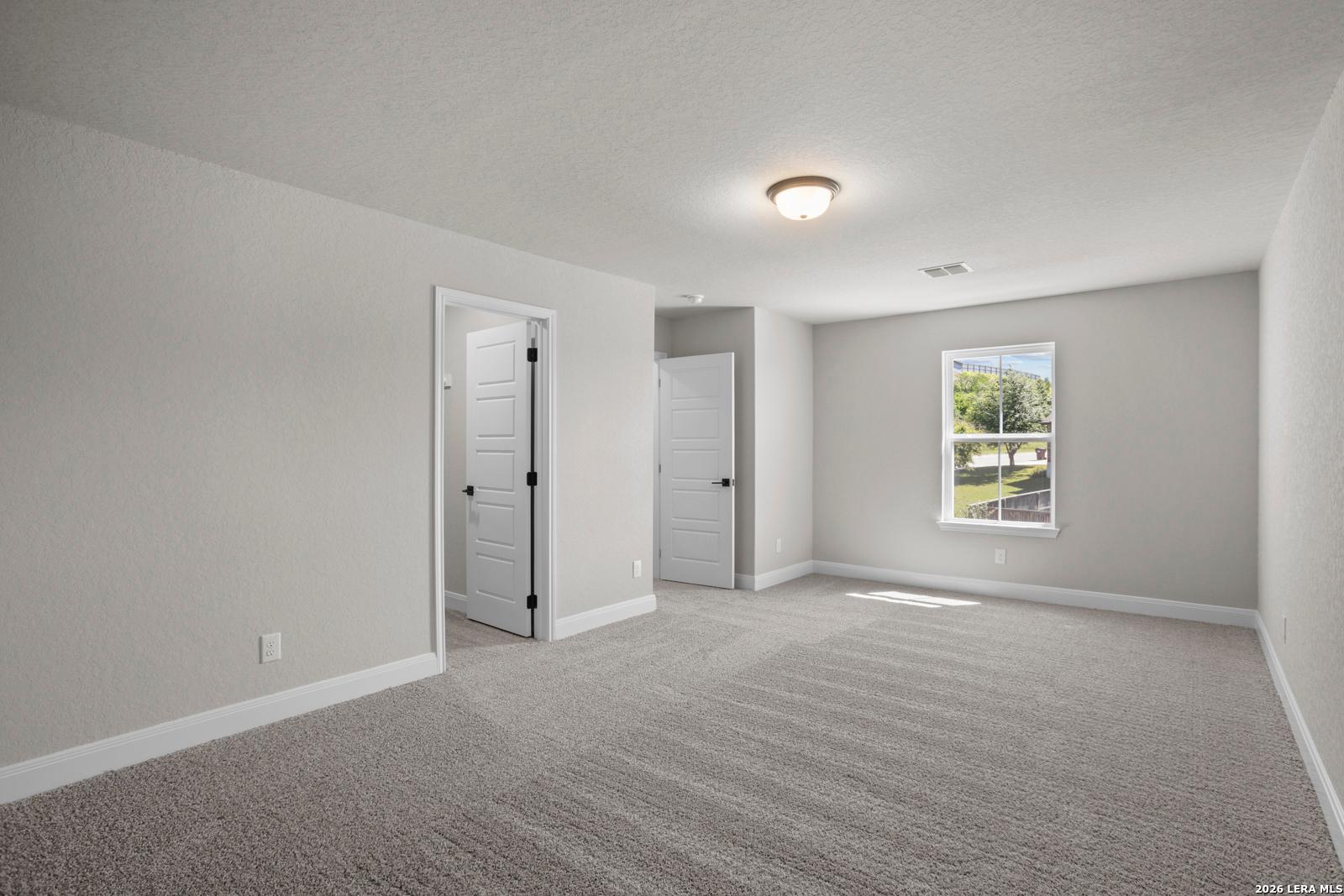 Spacious carpeted bedroom with neutral walls and natural light in The Jennings G floor plan at Ladera, San Antonio.