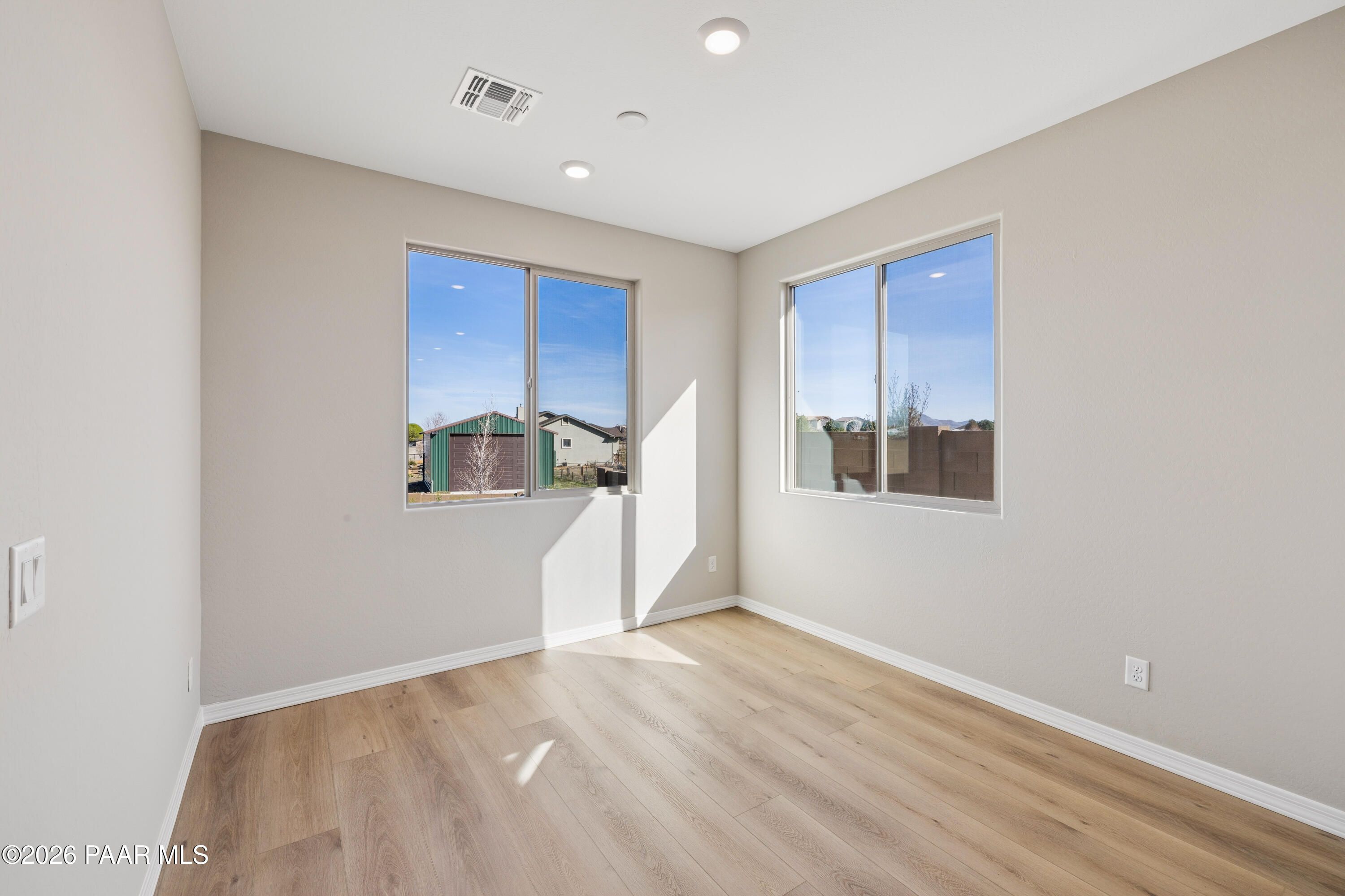 Bright secondary bedroom with large windows, beige walls, and light wood floors in Davidson Homes The Harmony A, Prescott Valley, Arizona