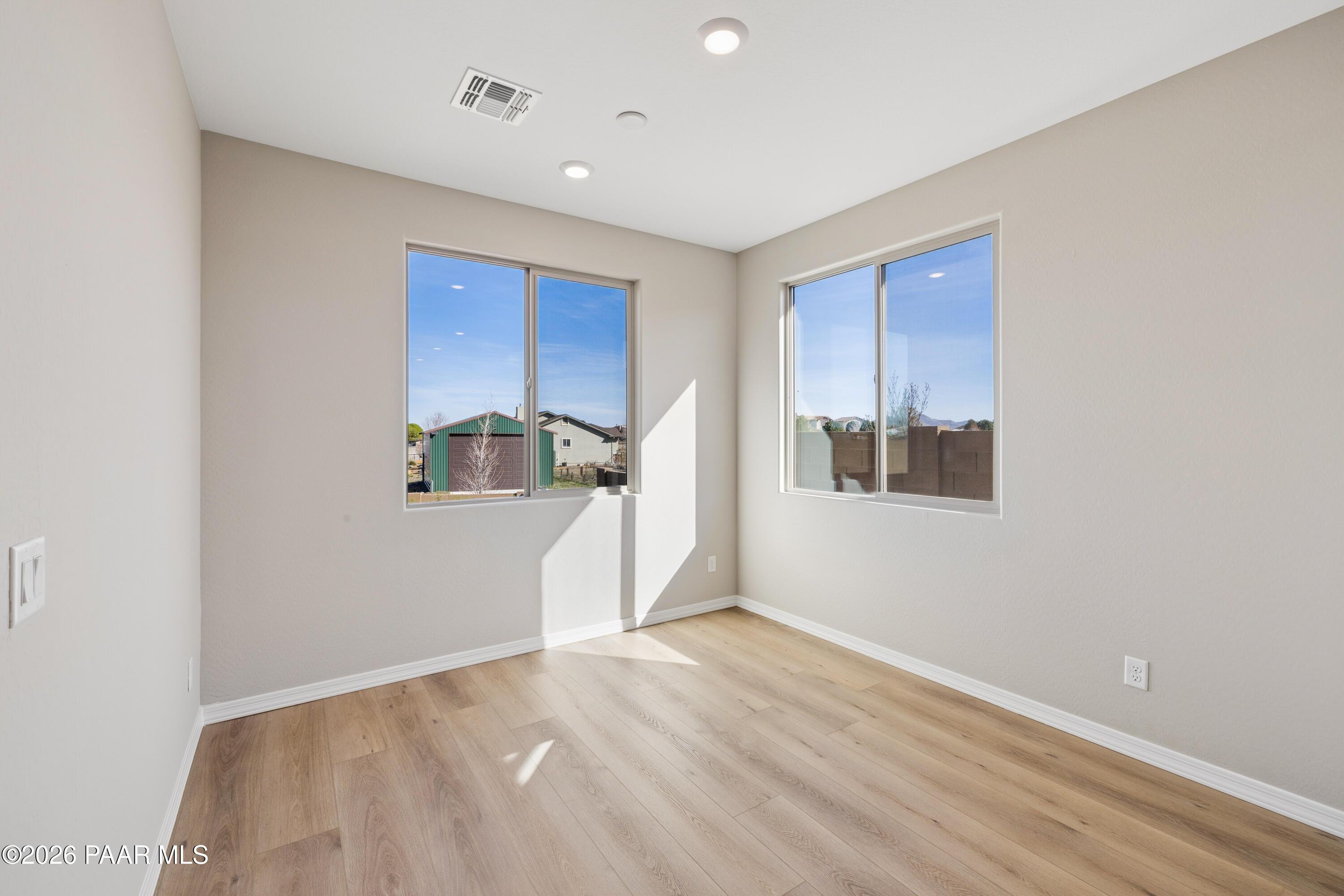Bright secondary bedroom with large windows, beige walls, and light wood floors in Davidson Homes The Harmony A, Prescott Valley, Arizona