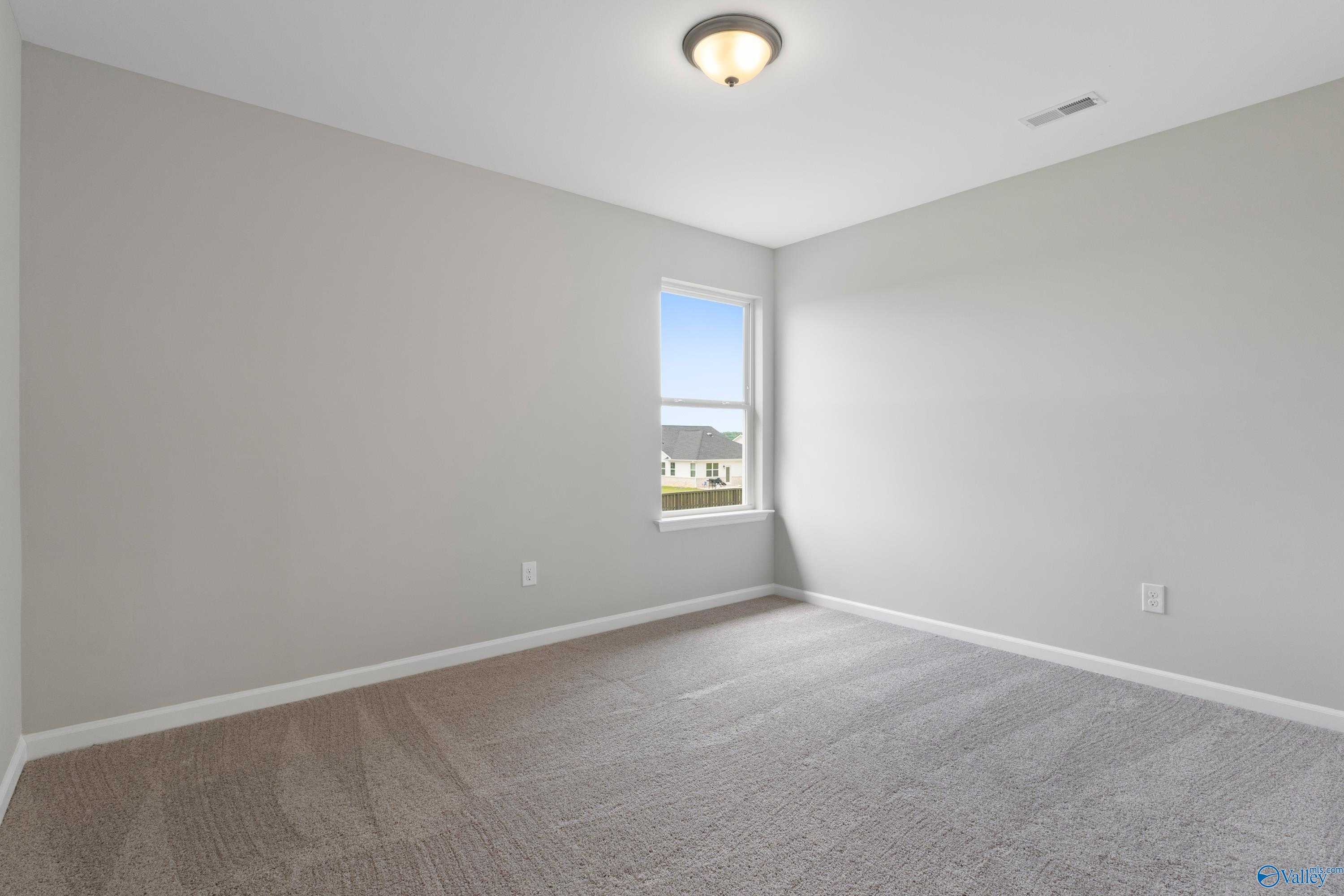 Bright secondary bedroom with large window, gray walls, and plush carpet in Davidson Homes The Dorado, Athens, Alabama