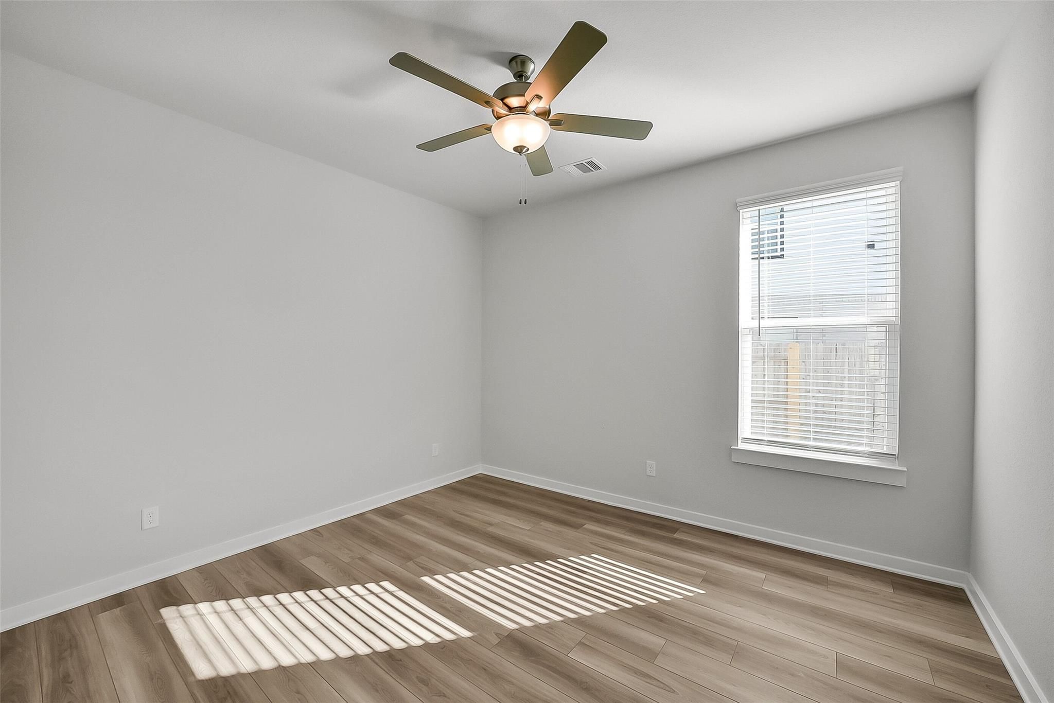 Bright secondary bedroom with ceiling fan, blinds window, and luxury vinyl plank floors in Davidson Homes The Acadia A, Sunterra, Katy, Texas