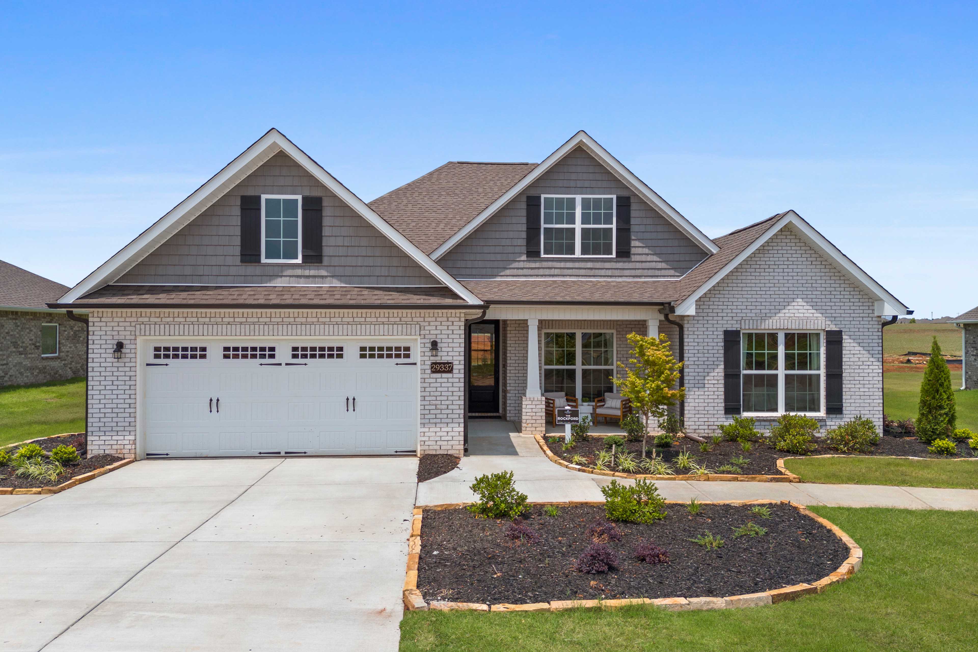Modern craftsman home exterior at Creekside in Harvest, Alabama with gray siding, brick accents, covered porch, and landscaped yard
