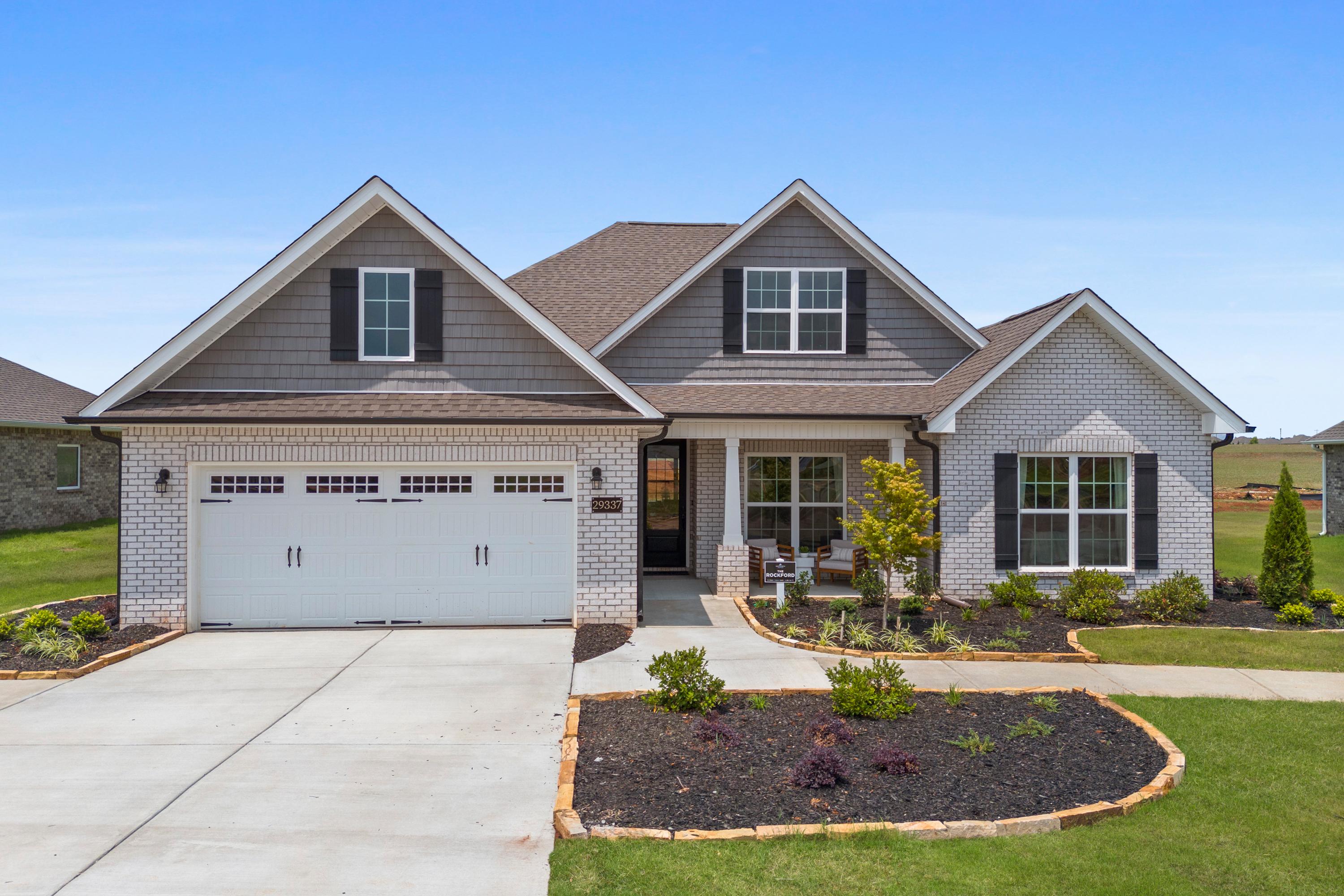 Modern craftsman home exterior at Creekside in Harvest, Alabama with gray siding, brick accents, covered porch, and landscaped yard