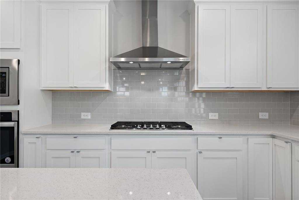 Modern white kitchen with quartz counters, subway tile backsplash, stainless gas range in Davidson Homes Hickory B, Winder, GA