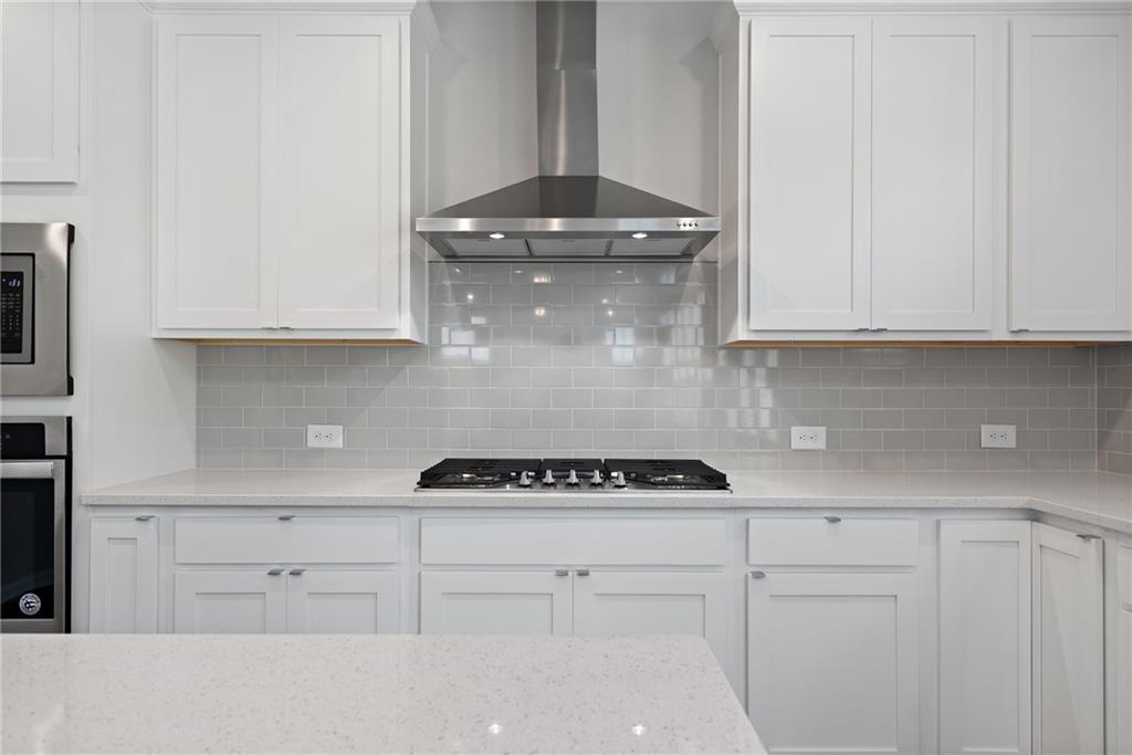 Modern white kitchen with shaker cabinets, quartz counters, subway tile backsplash, stainless appliances in The Hickory A, Winder, GA
