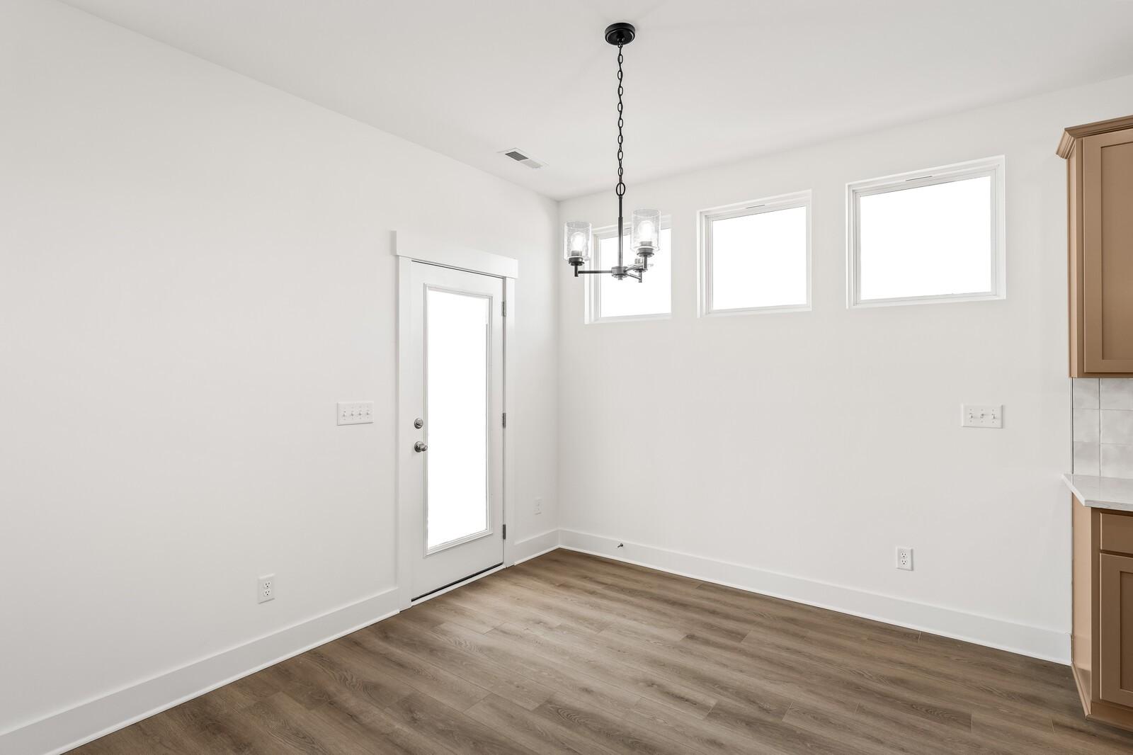 Bright breakfast nook with chandelier, large windows, French door, and beige cabinets in Davidson Homes The Ash A, Gallatin, TN