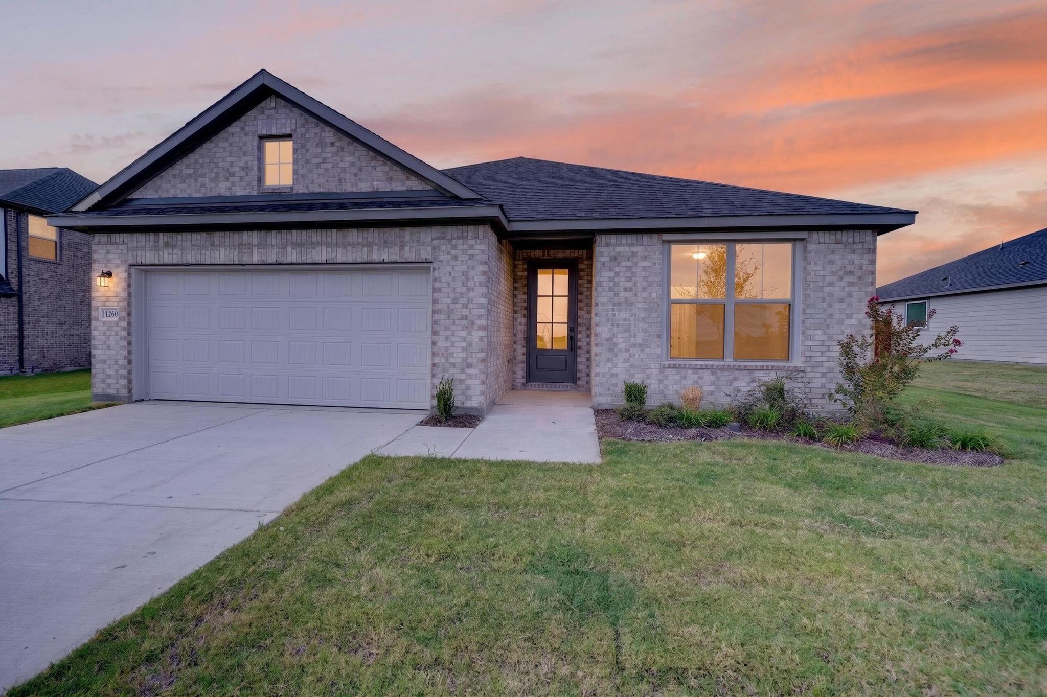 Single-story brick exterior with 2-car garage at dusk in Davidson Homes' The Holly F, Meadow Ridge Estates, Josephine, Texas