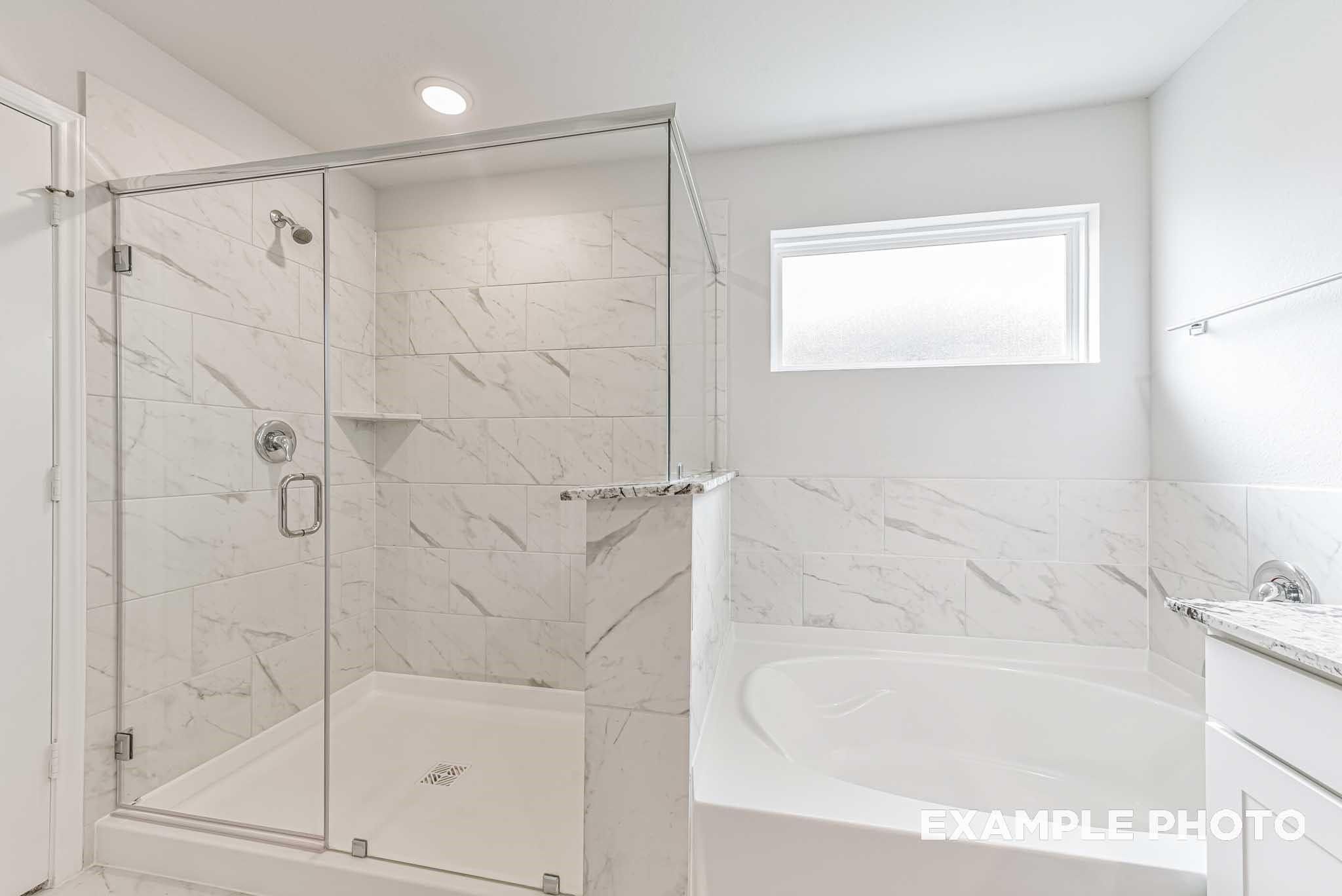 Elegant master bathroom featuring frameless glass shower, freestanding tub, and white marble tiles in Davidson Homes The Riviera A, Rosharon, Texas