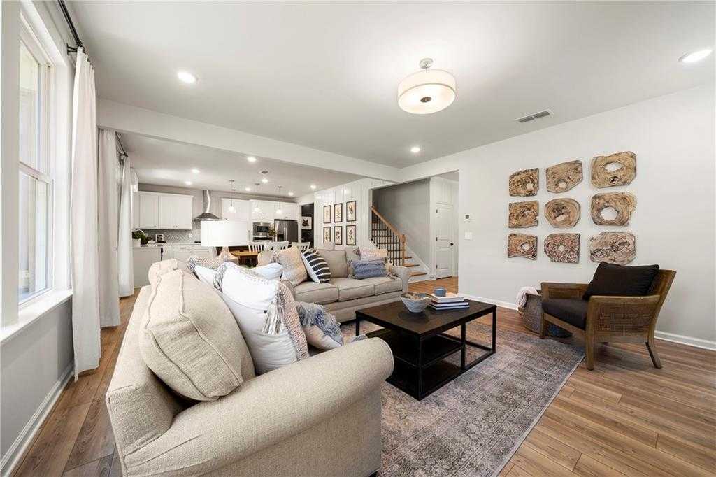 Cozy living room with beige sofa, coffee table, wall art, and open kitchen view in Davidson Homes The Hickory B, Dallas, Georgia