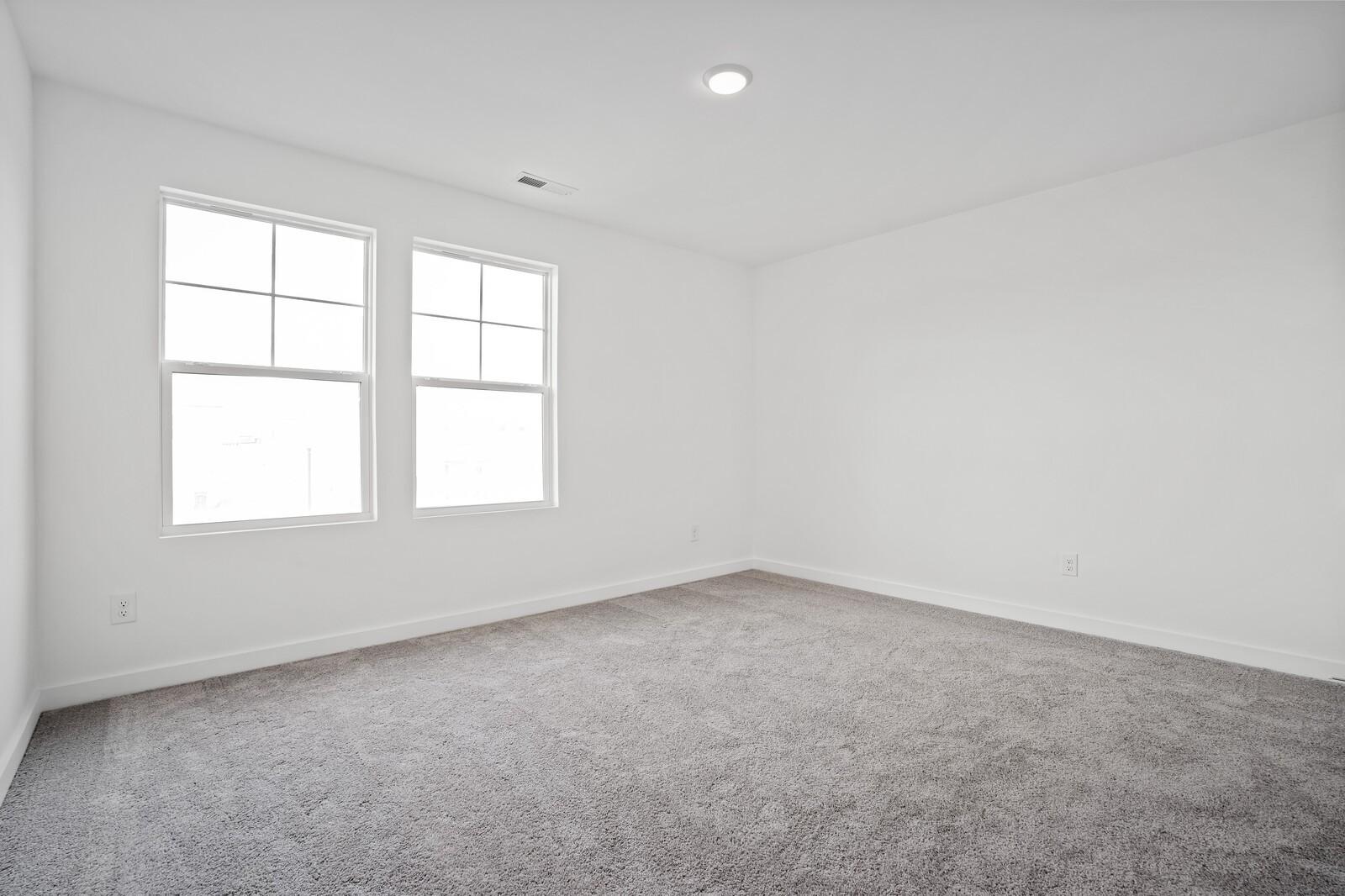 Bright, carpeted bedroom with white walls in The Logan C floor plan at Calista Farms in White House, Tennessee.