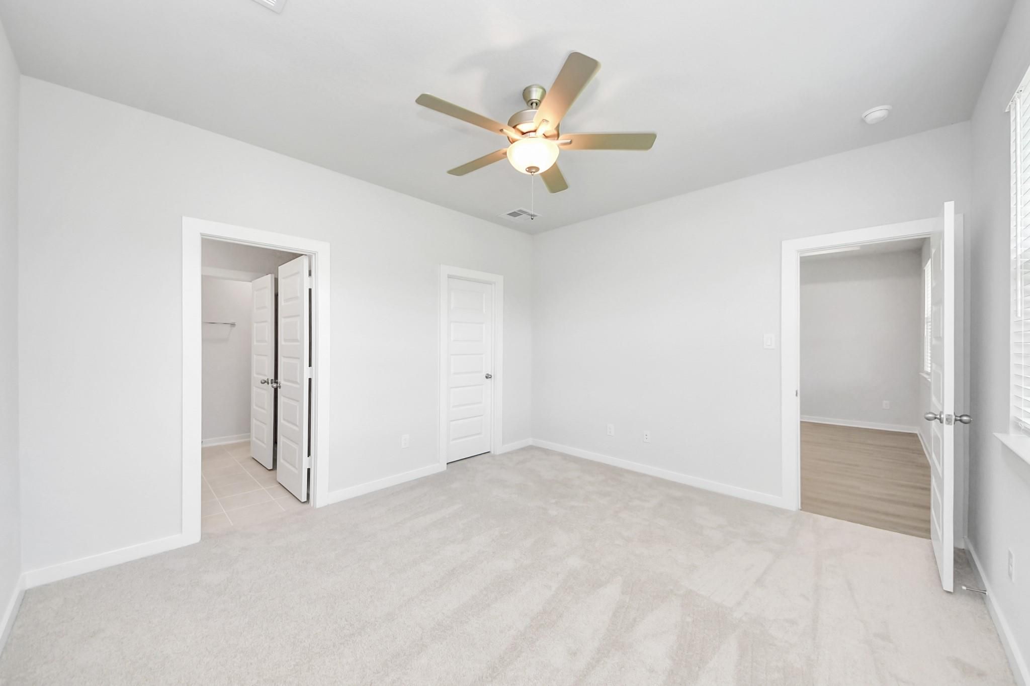 Bright secondary bedroom with plush carpet and ceiling fan in The Frio F plan at Liberty Estates, Cleveland, Texas.