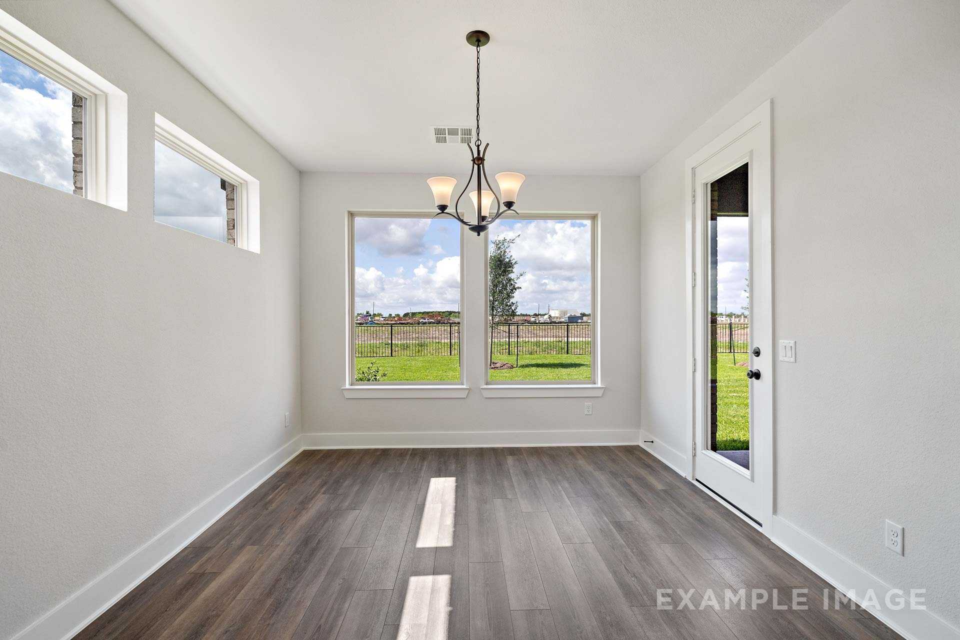 Bright sunroom in The Victoria A home showcasing large windows with Texas field views, hardwood floors, and chandelier lighting