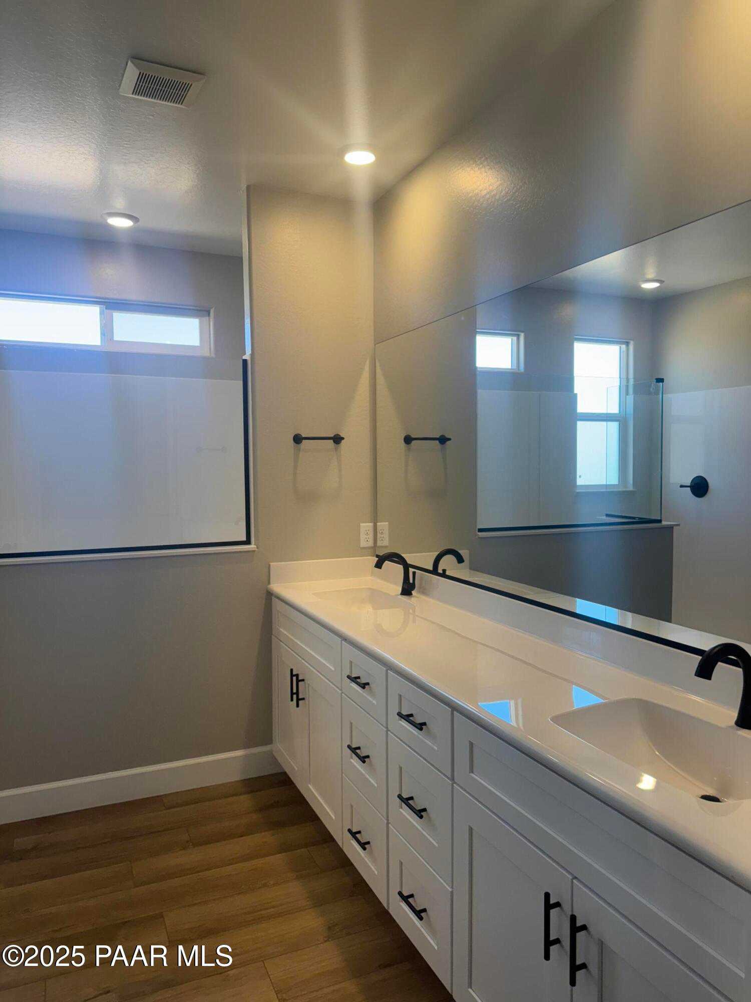 Modern master bathroom double vanity with white shaker cabinets, black faucets, and frameless mirror in Evermore Homes The Summit B, Prescott Valley, AZ