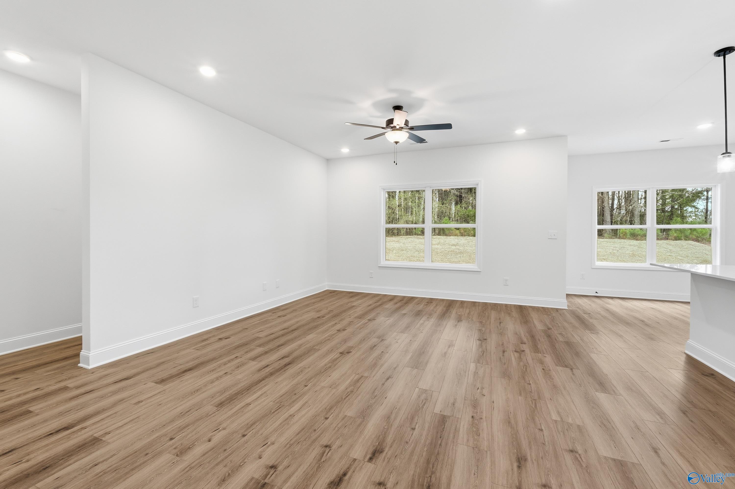 Bright open-concept living area with wood-look flooring in The Asheville C floor plan at The Highlands in Arab, Alabama.