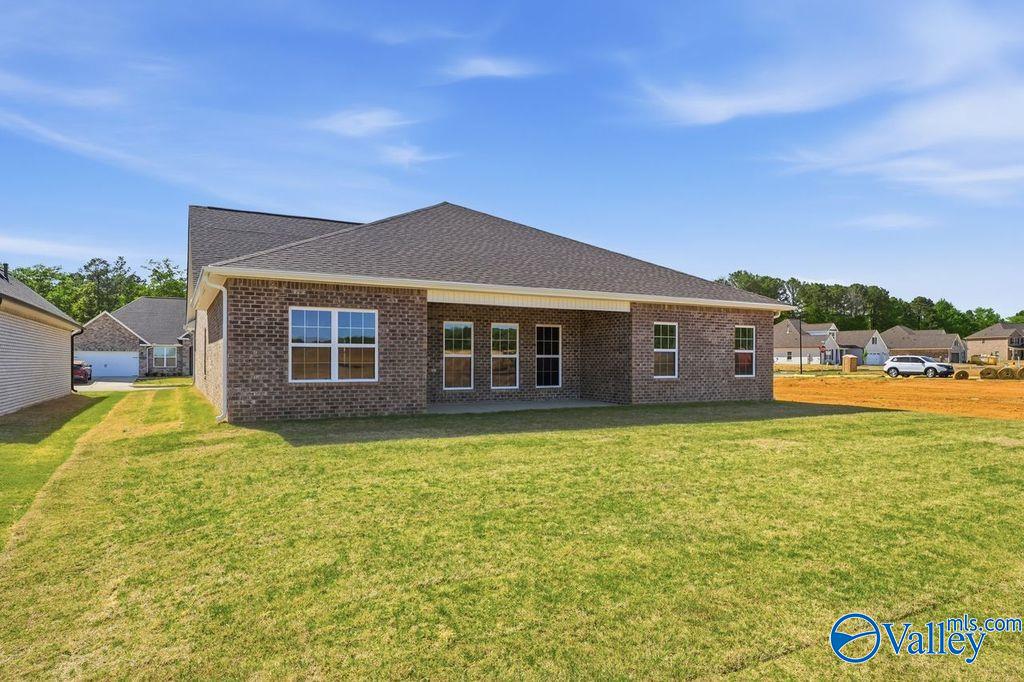 Single-story brick home with covered patio, large windows, and lush green yard in Cain Park, Hartselle, Alabama - The Harrison by Davidson Homes