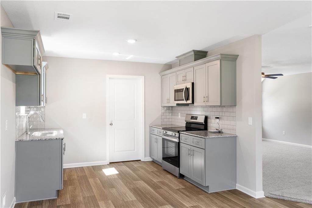 Modern kitchen with gray cabinets, granite countertops, and stainless appliances in The Washington floor plan, Phenix City.