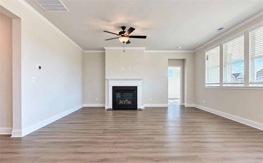 Spacious great room with wood-look flooring, fireplace, and ceiling fan in Davidson Homes The Harrison H, Wehunt Meadows, Hoschton, GA