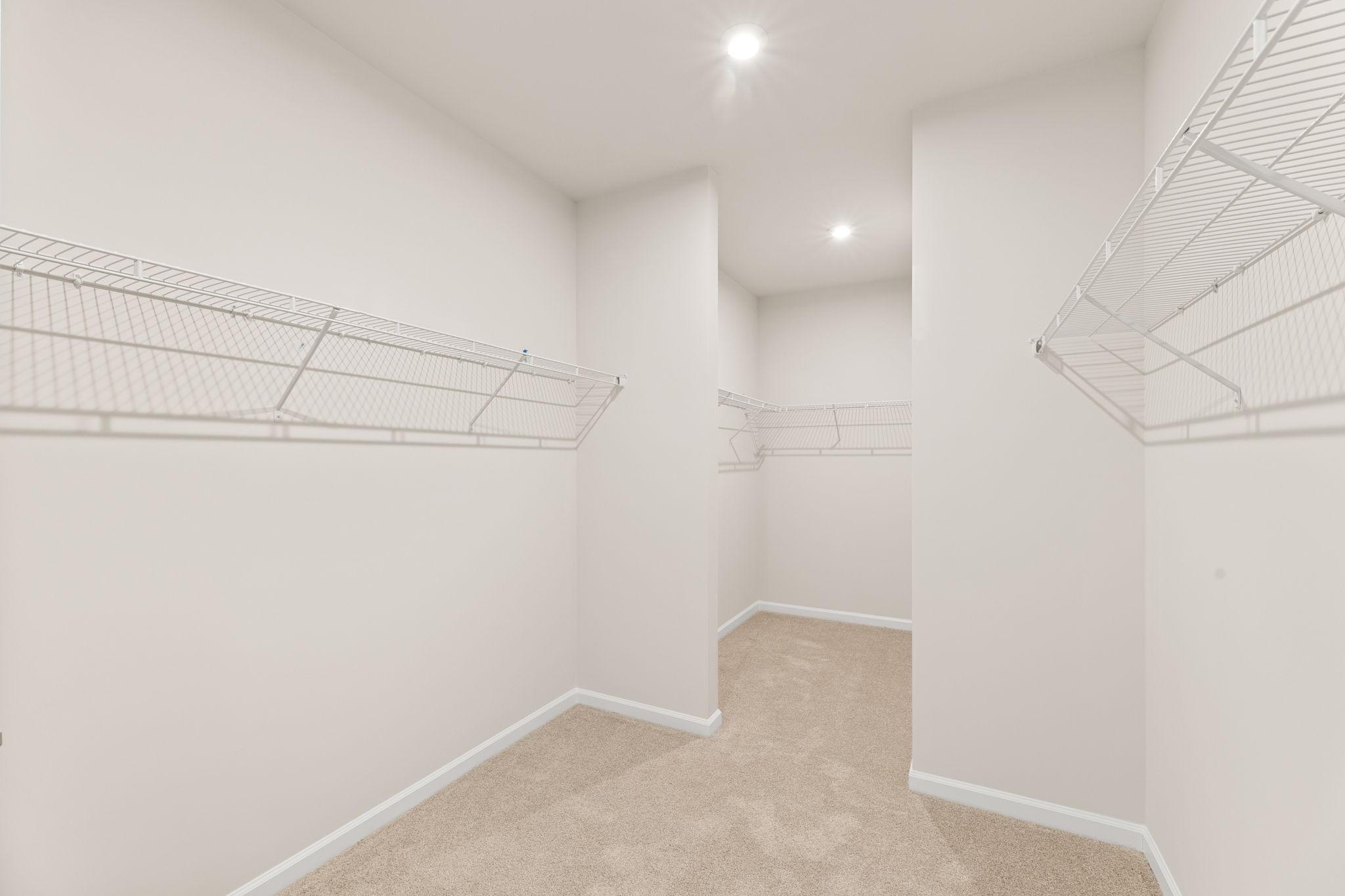 Spacious walk-in closet with wire shelving, carpeted floor, and recessed lights in Davidson Homes The Glenwood C, Loganville, GA