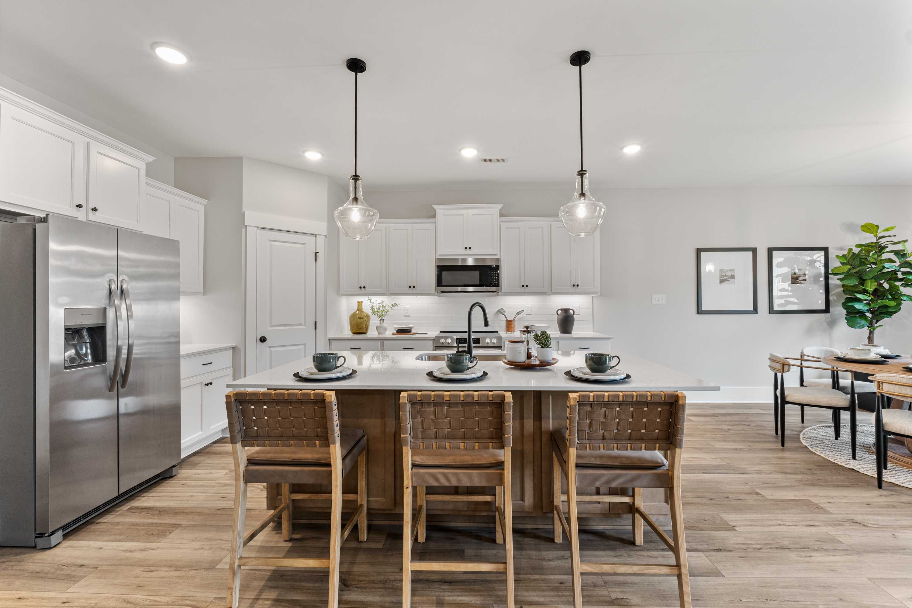 Contemporary kitchen at River Road Estates in Decatur, Alabama with white cabinets, large island, pendant lights, and hardwood floors