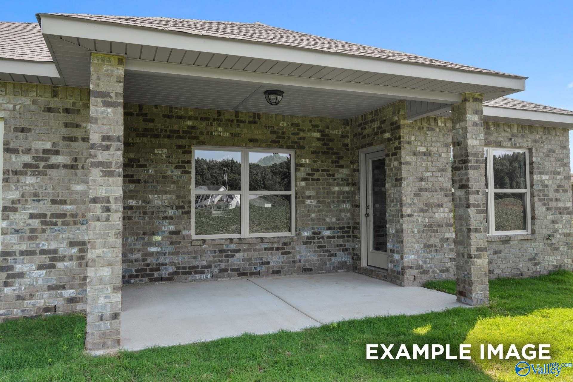 Covered brick front porch with columns, large windows, and entry door on The Asheville 3-bedroom home in The Highlands, Arab, Alabama
