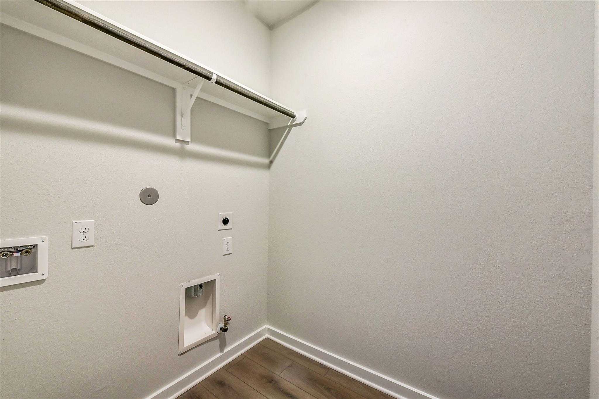 Bright laundry room with built-in rod, shelves, and washer/dryer hookups in Davidson Homes The Comal G, Dayton, Texas