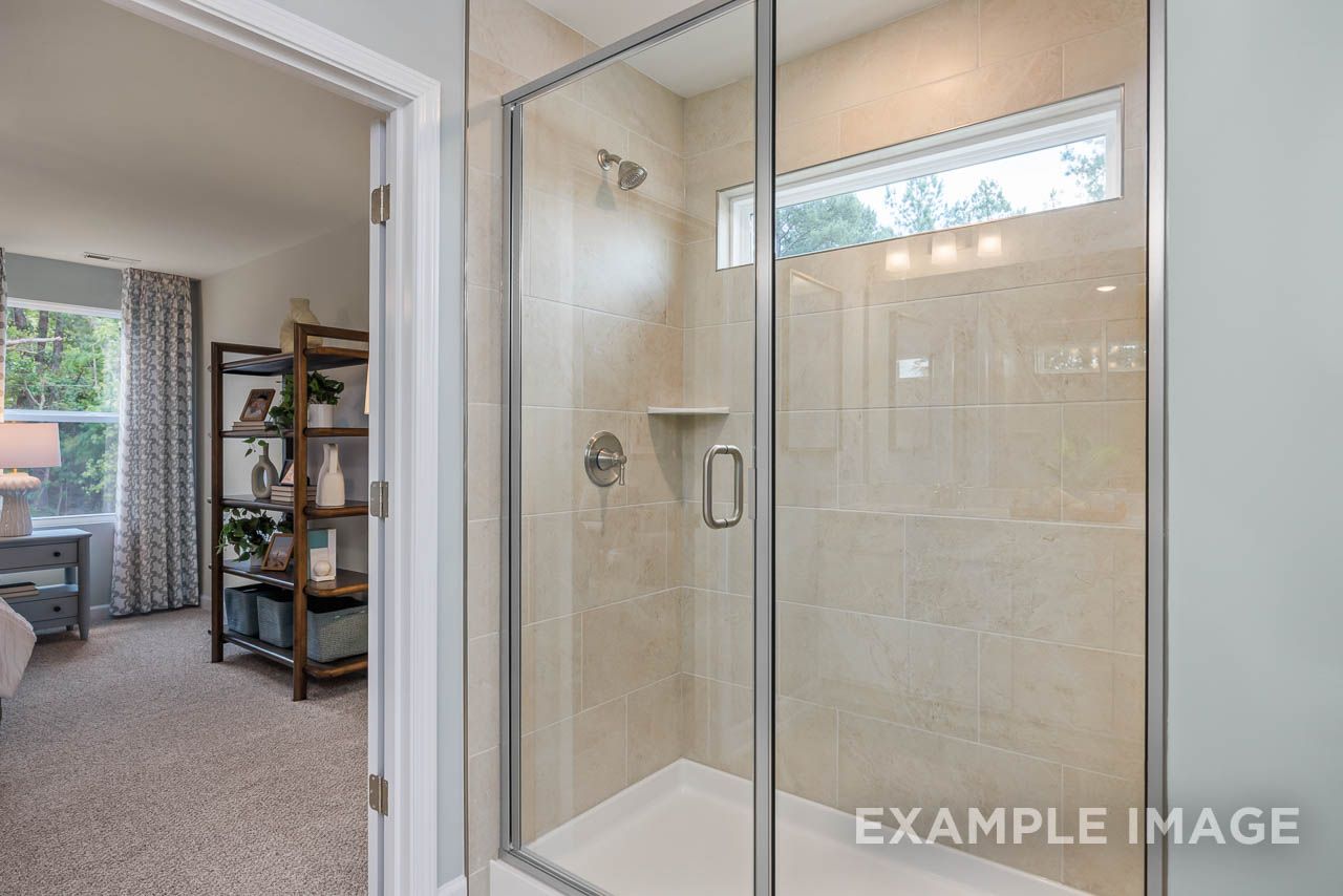 Glass walk-in shower with beige tile in The Willow C-BF master bathroom by Davidson Homes in Mt. Juliet, TN.